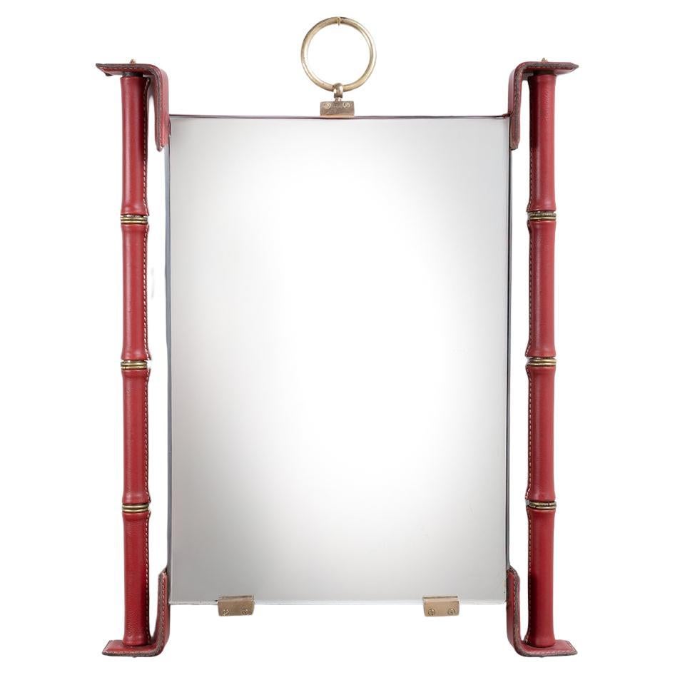Mirror fully covered in red leather with saddle stitching by Jacques Adnet