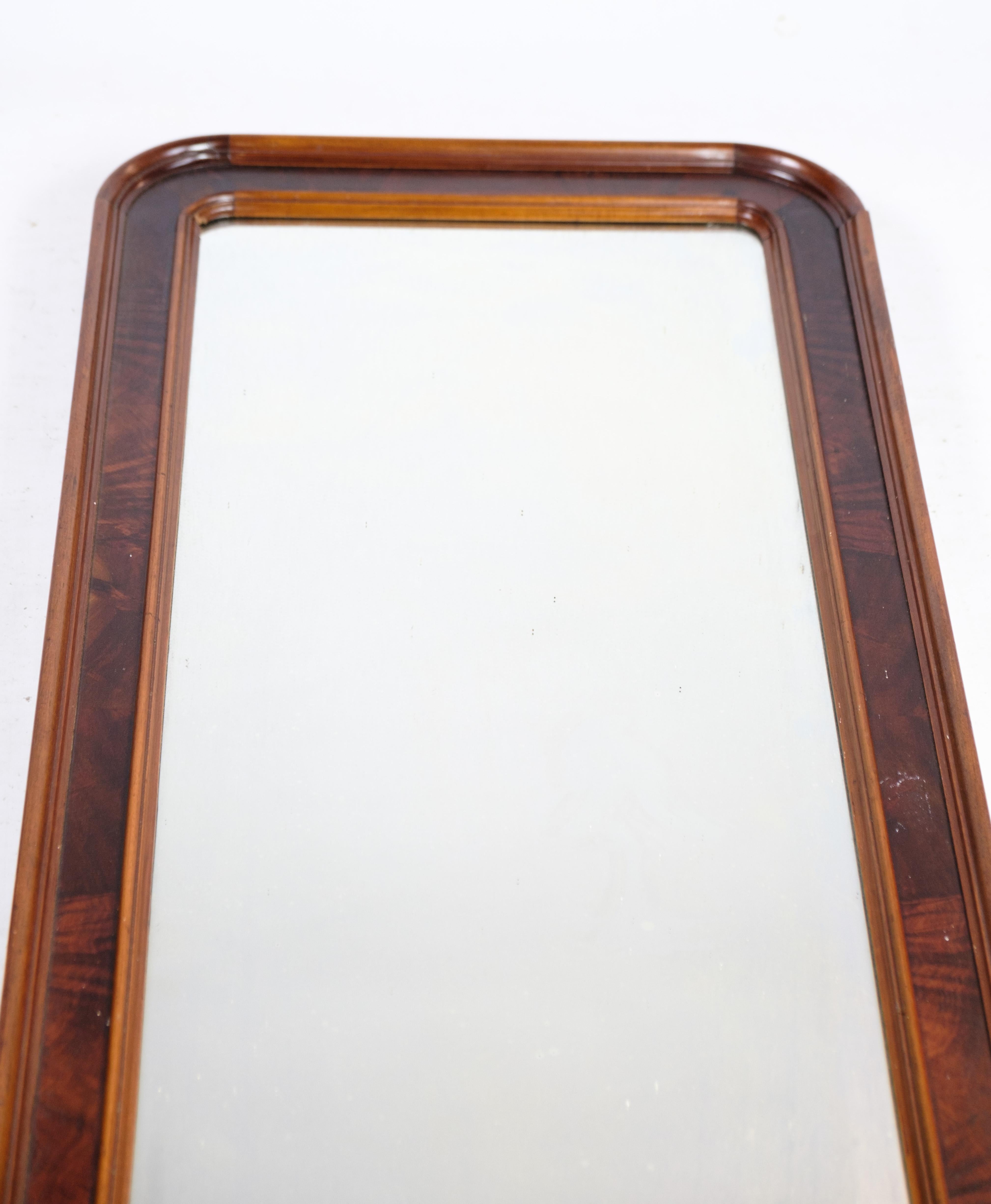 The Mirror of hand-polished mahogany is a beautifully crafted piece of art from the late Empire period. It is made in Denmark, dating back to the 1890s. The mahogany wood is carefully hand-polished, giving it a smooth and lustrous finish. The frame