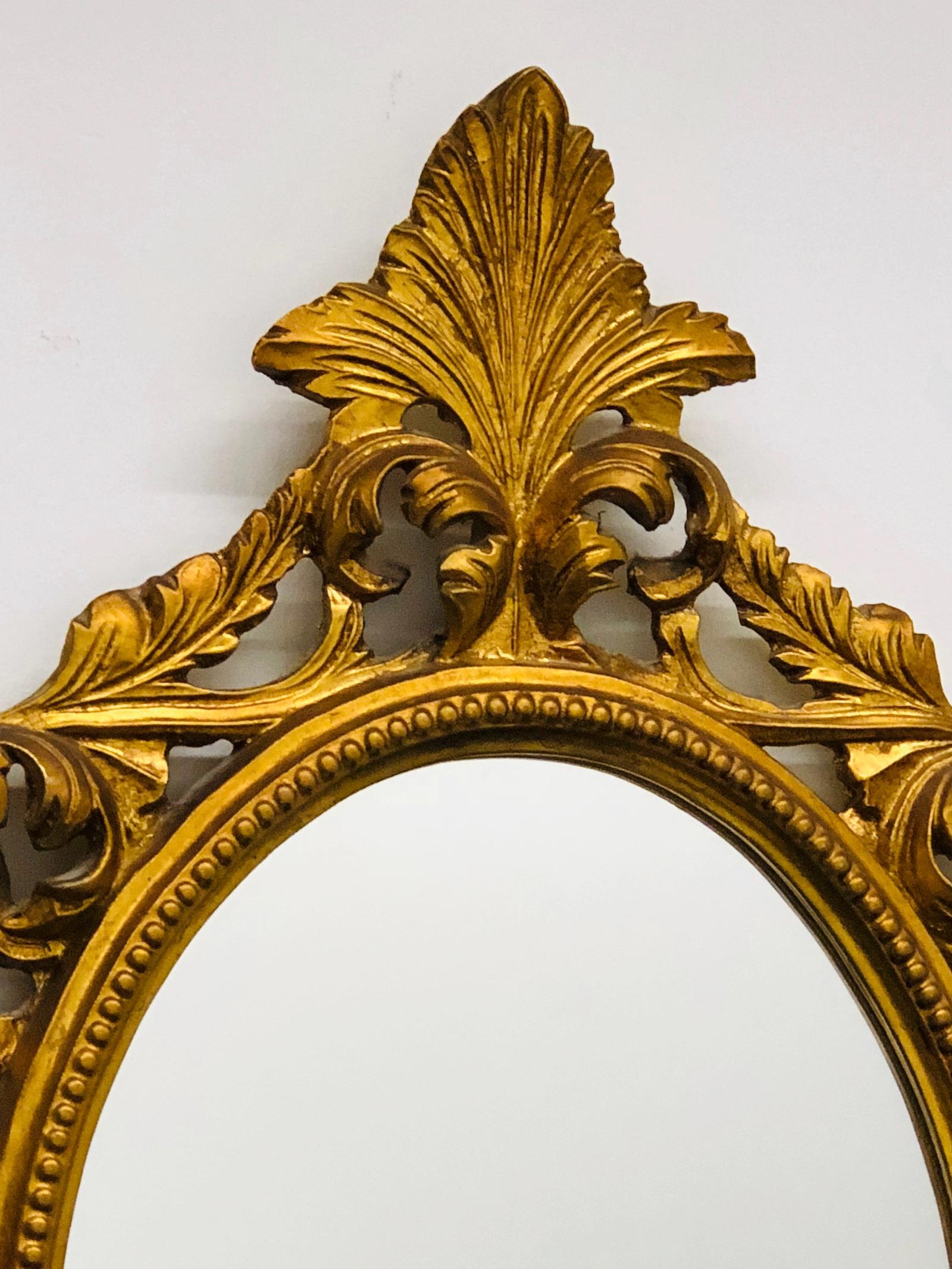 Stunning Hollywood Regency style carved mirror. The giltwood frame surrounds a glass mirror. Made in Italy.