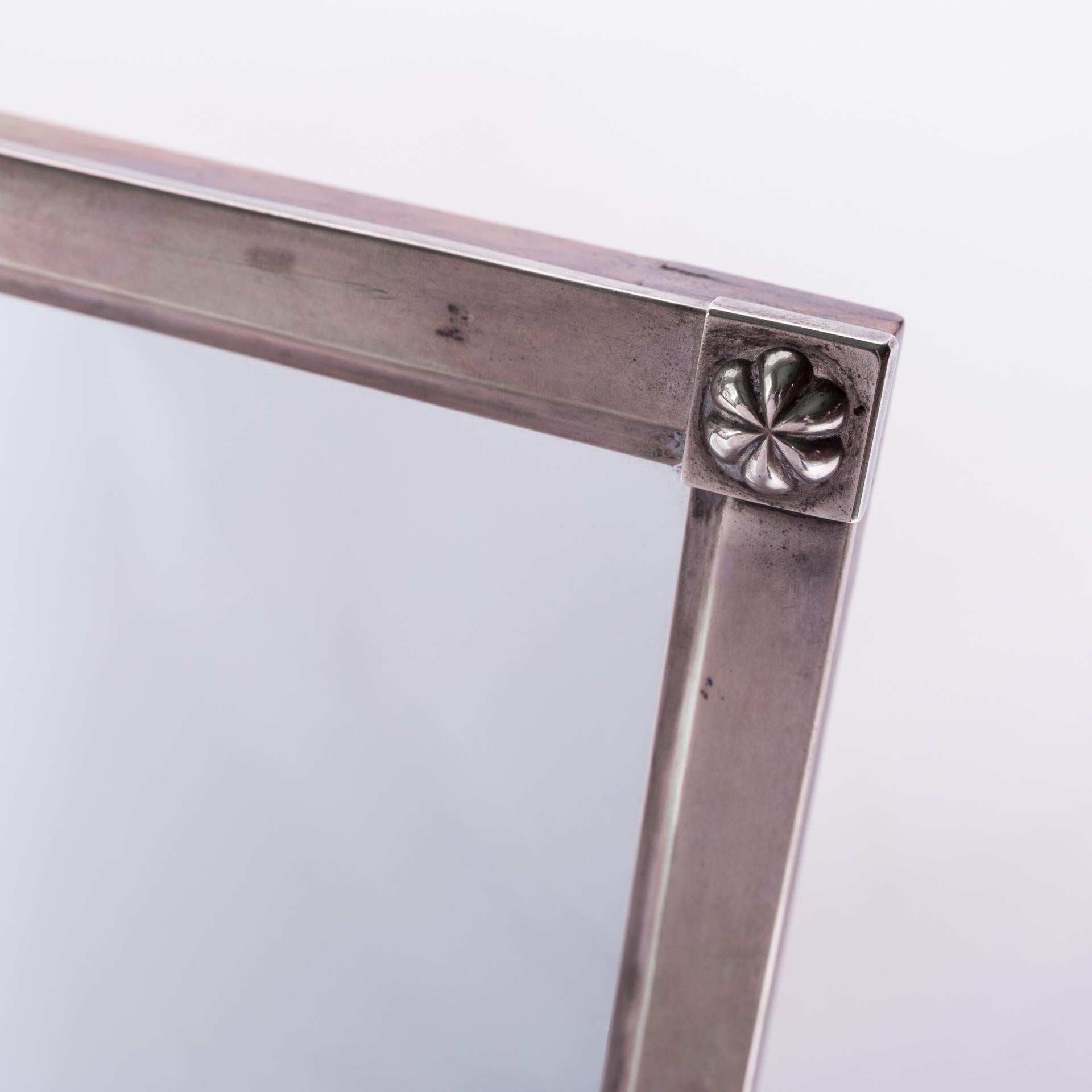 A mirror that is an early example of the Biedermeier style. Smooth silver frame with a beautiful gloss. Decorative elements in the form of rosettes placed on the corners of the frame. Signed at the top of the B.E frame, they were probably the