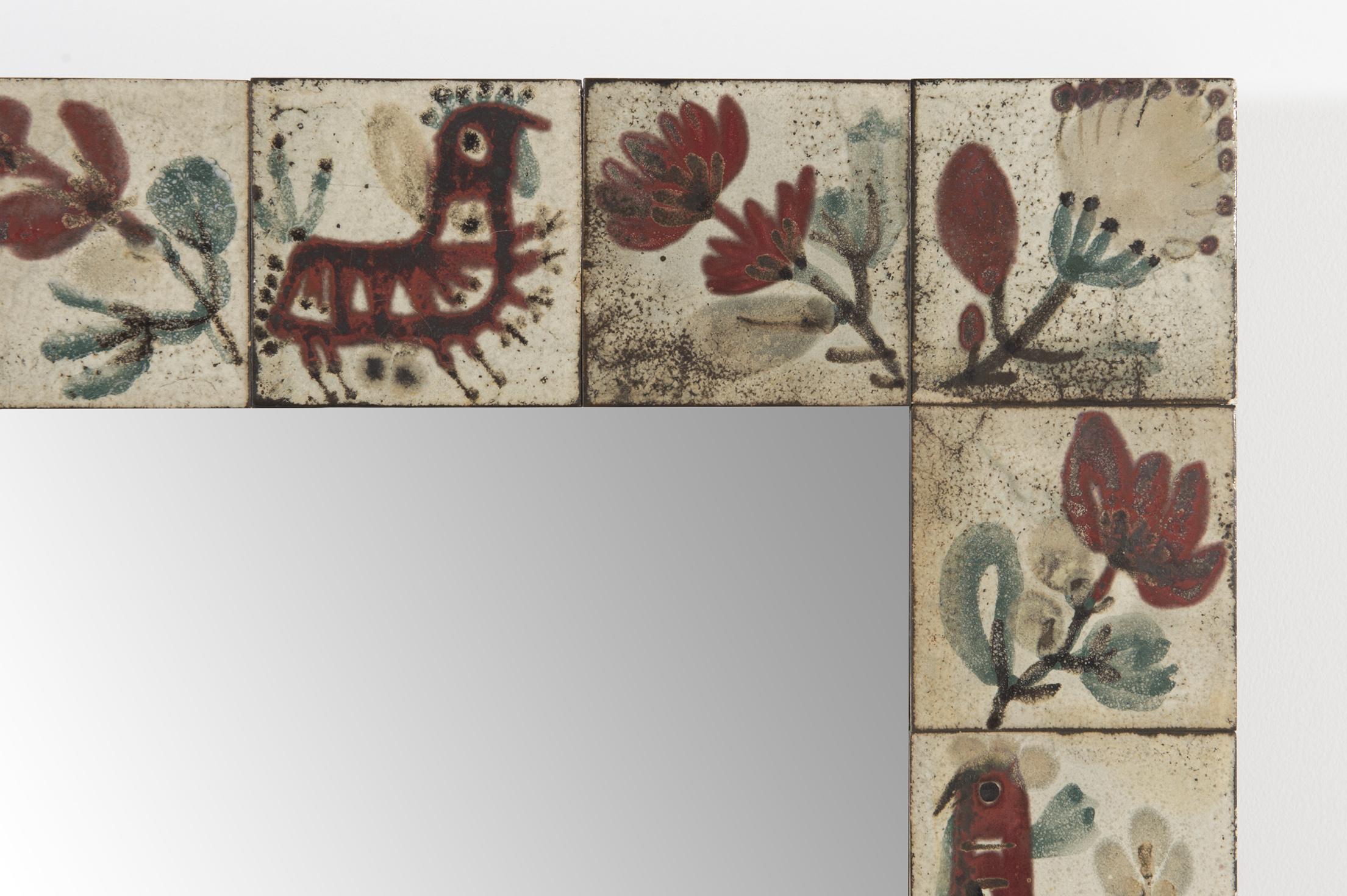 Mirror framed with polychrome ceramic tiles with motifs depicting a variety of flowers and imaginary animals. The colours used are the typical green and dark red and the style is 