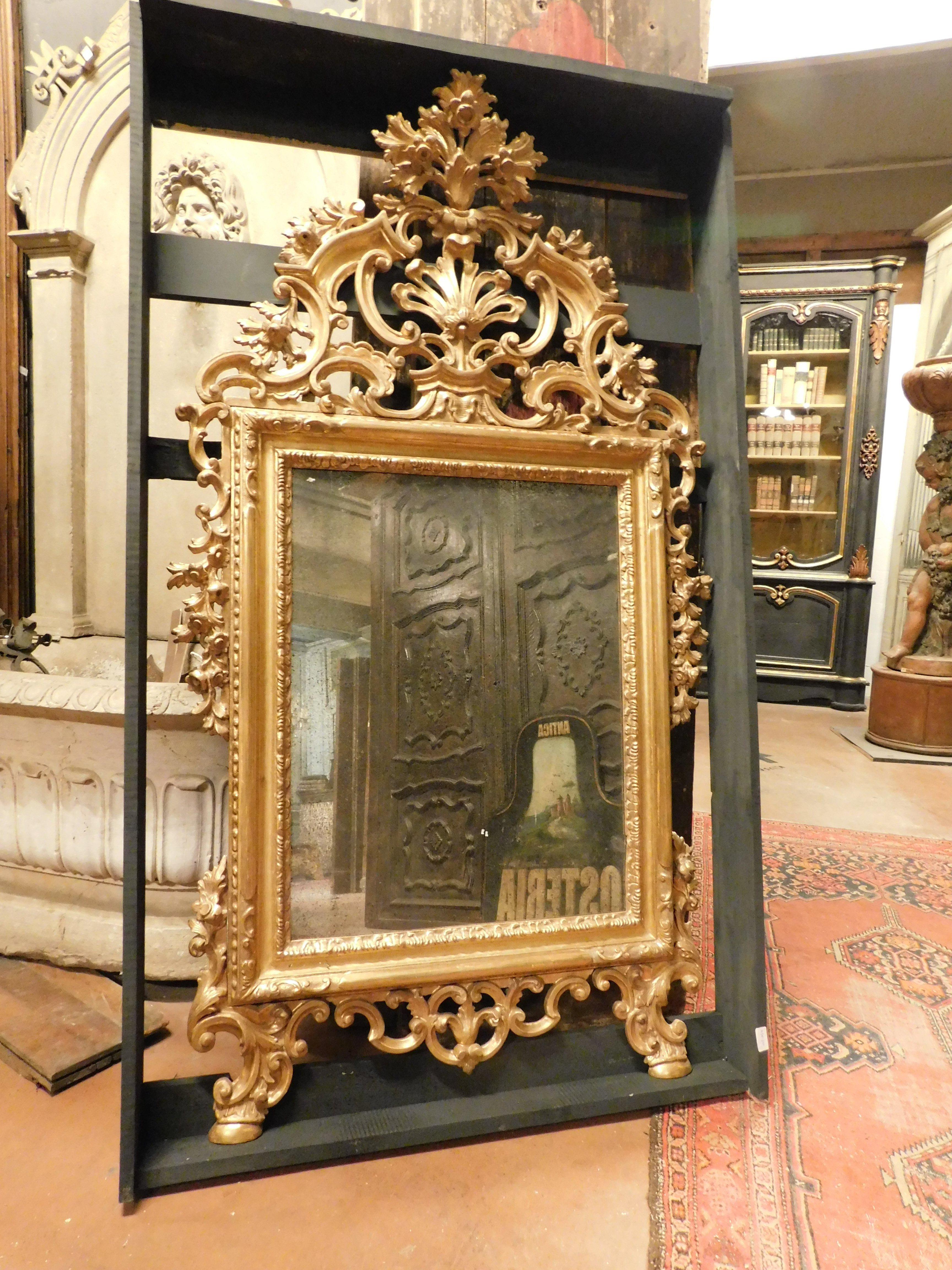 Ancient mirror in gilded wood, mirror above fireplace or wall, enriched by frieze perforated with volutes and carved floral and leafy elements, hand-built in the 1800s, from Naples (Italy), maximum dimensions cm W 90 x H 163.
Very rich and very