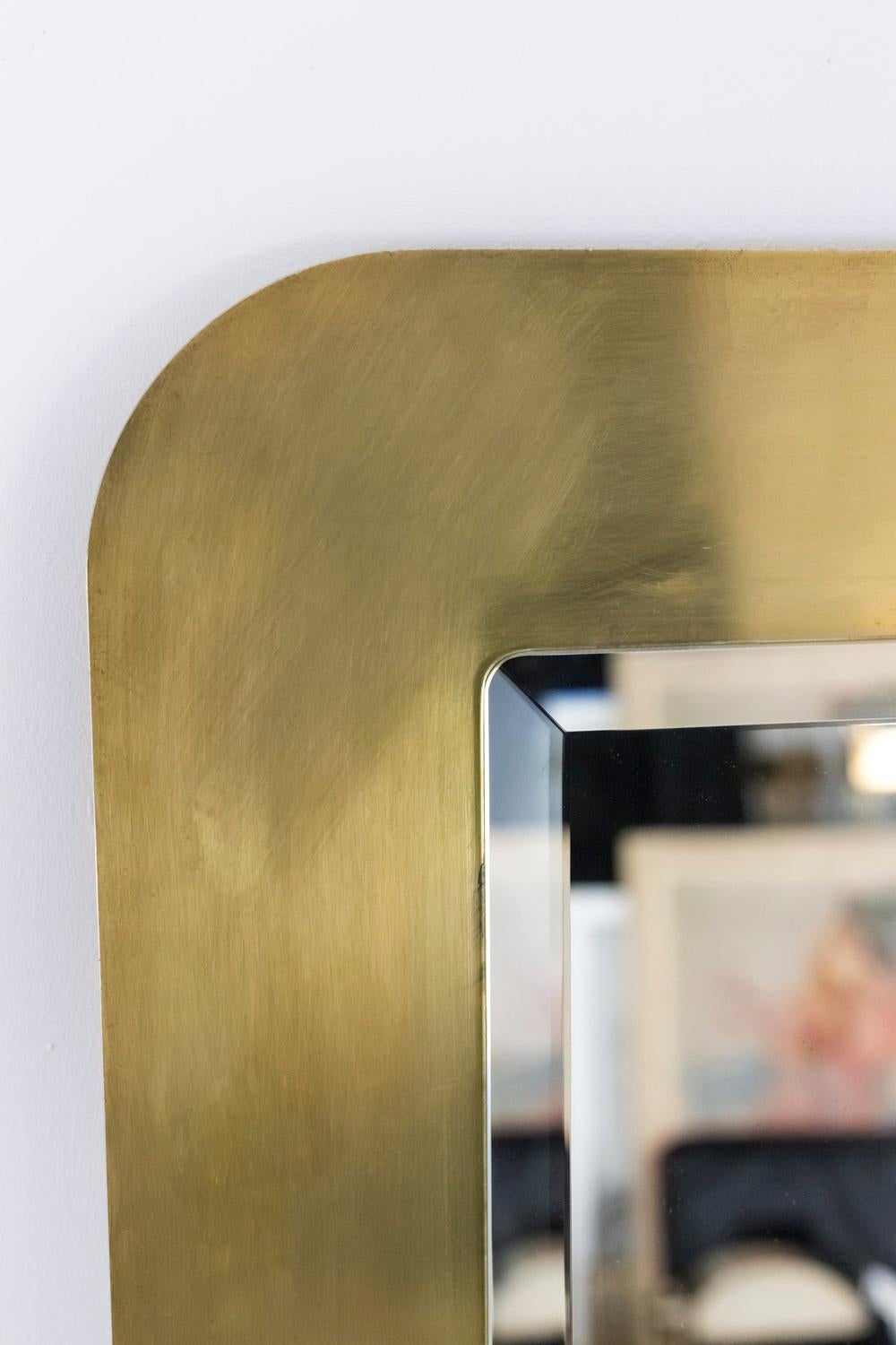 Beveled gilt brass brushed mirror in a rectangular shape with curved corners.

Italian work realized in the 1970s.
