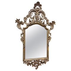 Mirror in silver lacquered wood, richly carved with open carved top, Italy