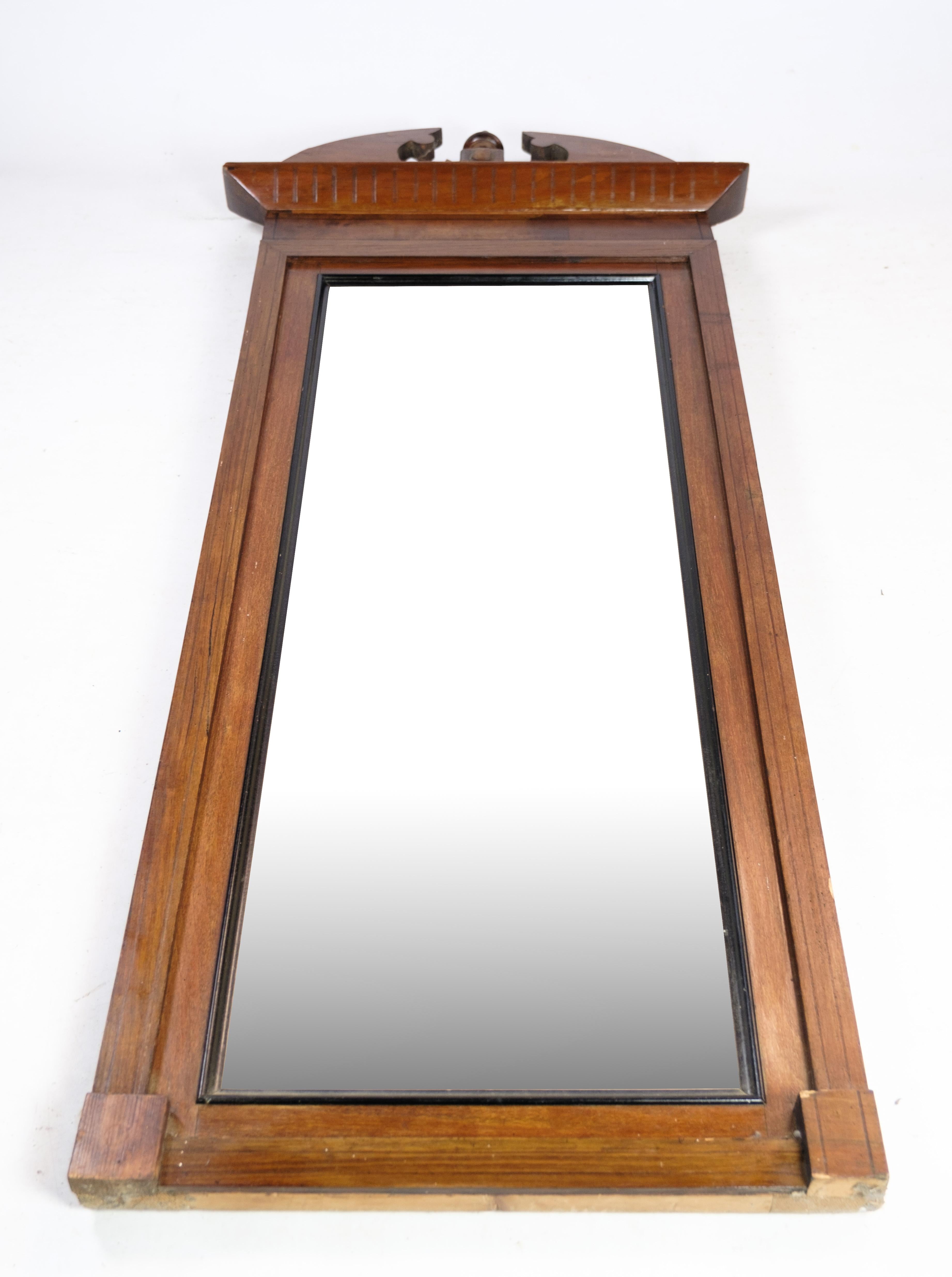 Der Spiegel aus handpoliertem Mahagoni ist ein schönes und einzigartiges Möbelstück aus der späten Empirezeit. Dieser Spiegel wurde um 1840 in Dänemark hergestellt und zeichnet sich durch komplizierte Schnitzereien aus, die seine Eleganz und seinen