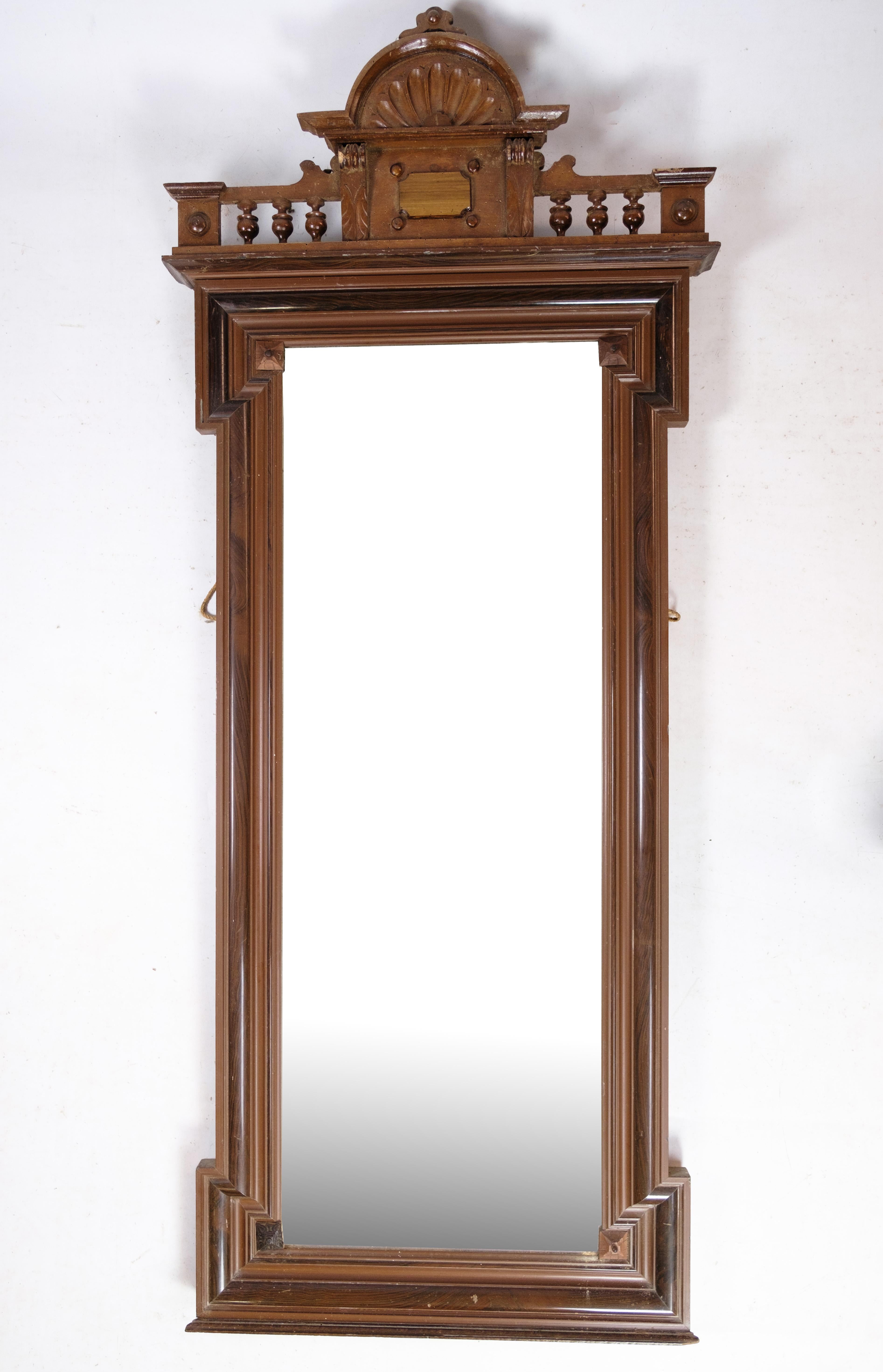 This beautiful hand-polished mahogany mirror is from the late Empire period and was crafted in Denmark around the 1840s. It features intricate carvings along the frame, adding a touch of elegance to the piece. The deep, rich color of the mahogany