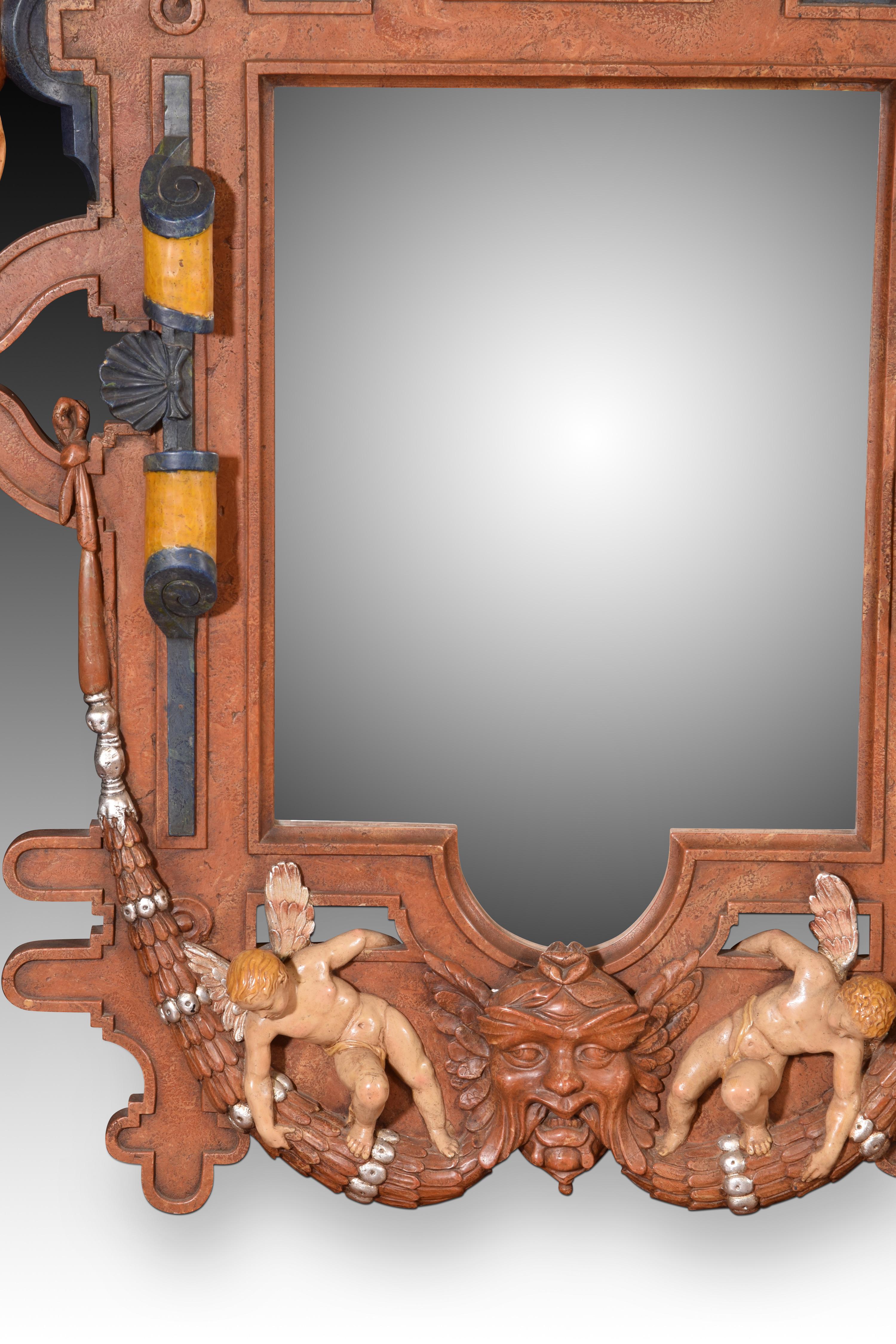 Mirror. Molded and polychrome alabaster. Twentieth century. 

Wall mirror made of alabaster molded with polychrome that has a frame of architectural elements of classicist influence and a series of figurative elements that respond to the same