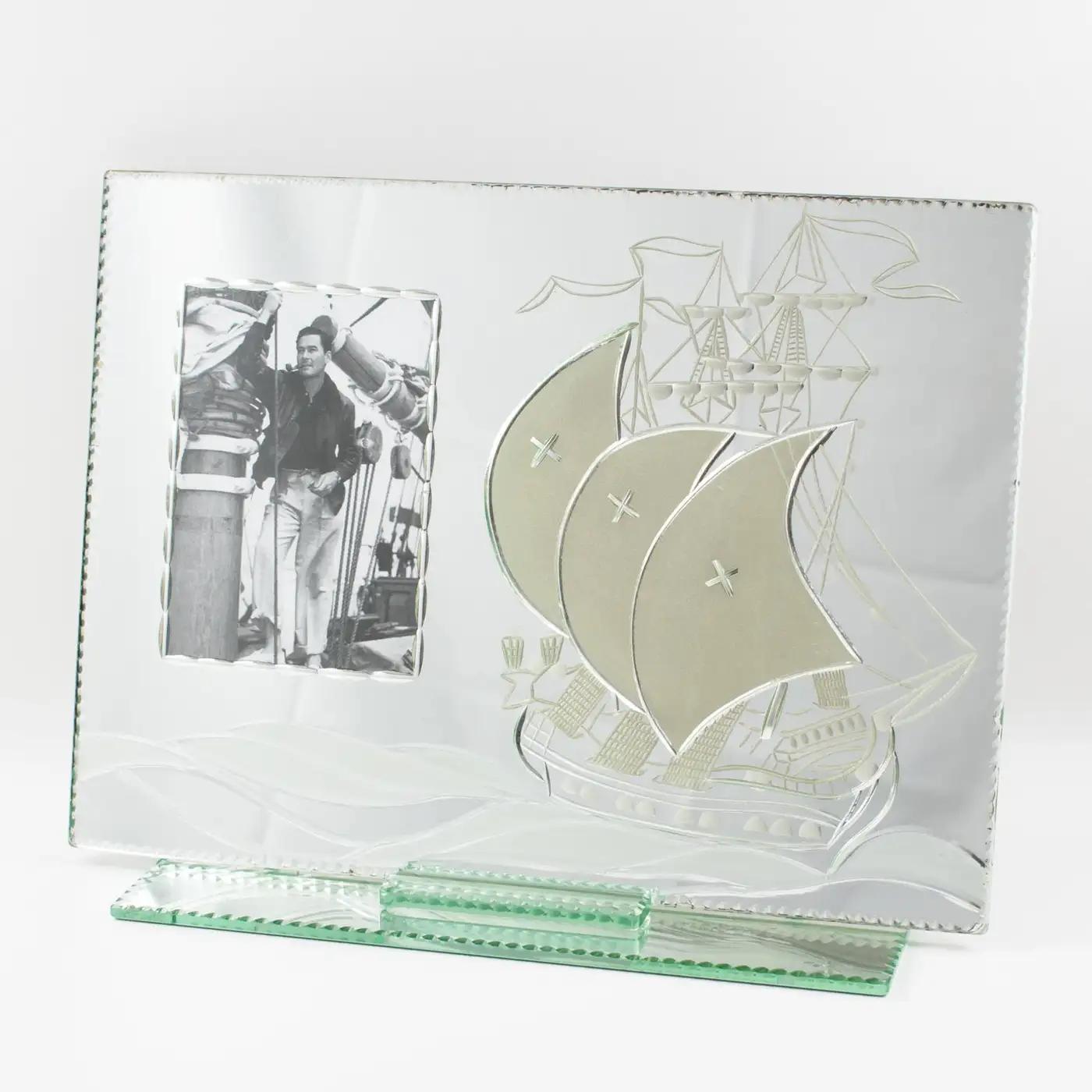 This stunning 1940s large silver mirror glass picture photo frame features a separate mirrored glass base with beveling all around supporting a mirrored glass sheet with a reverse etched antique galleon sailing boat. The design is adorned with