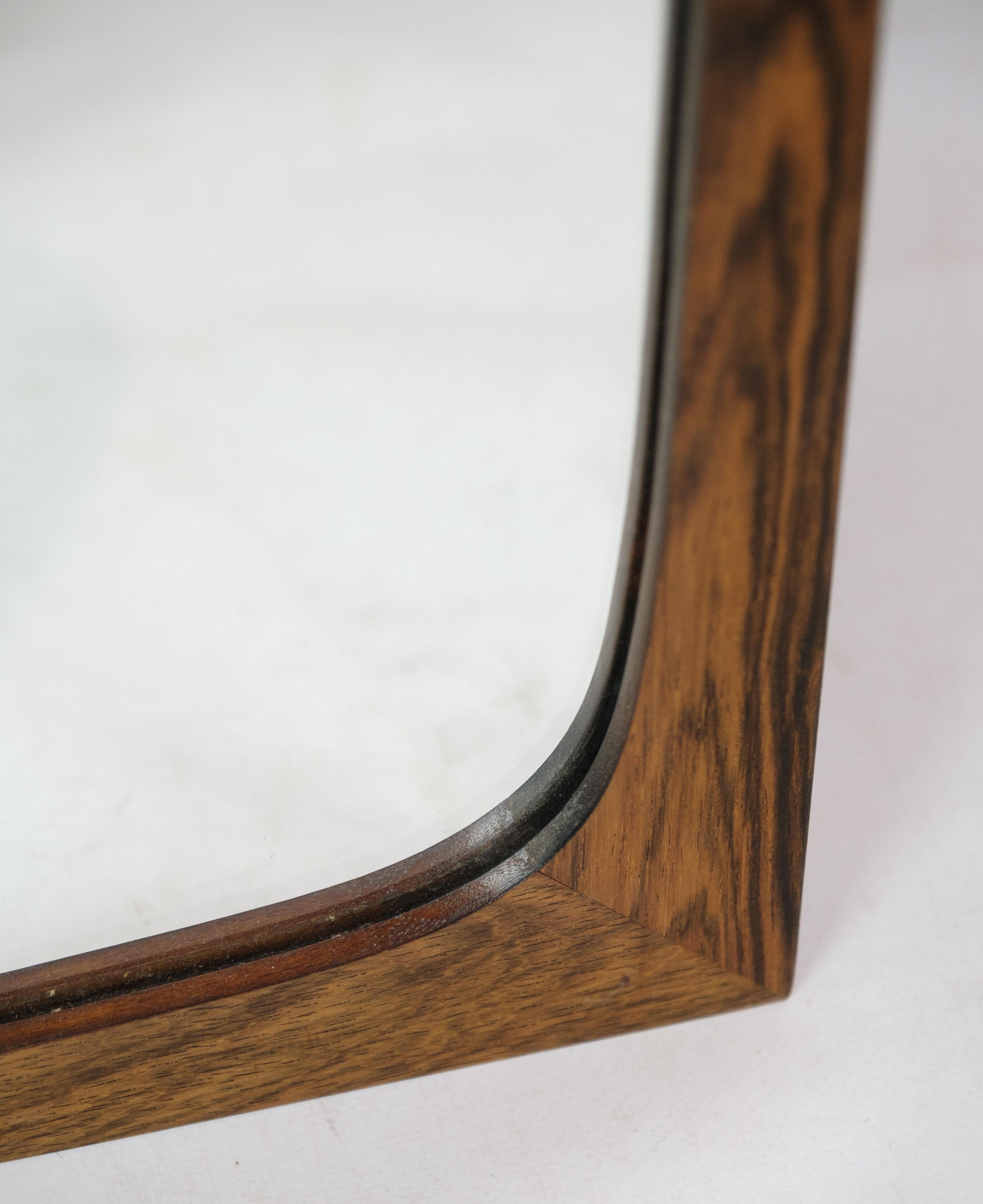 This elongated mirror, crafted from rosewood, is a fine example of Danish design from around the 1960s. With dimensions of H:97 cm and W:42 cm, it exudes the sleek and minimalist aesthetic characteristic of mid-century modern design. The rich hue