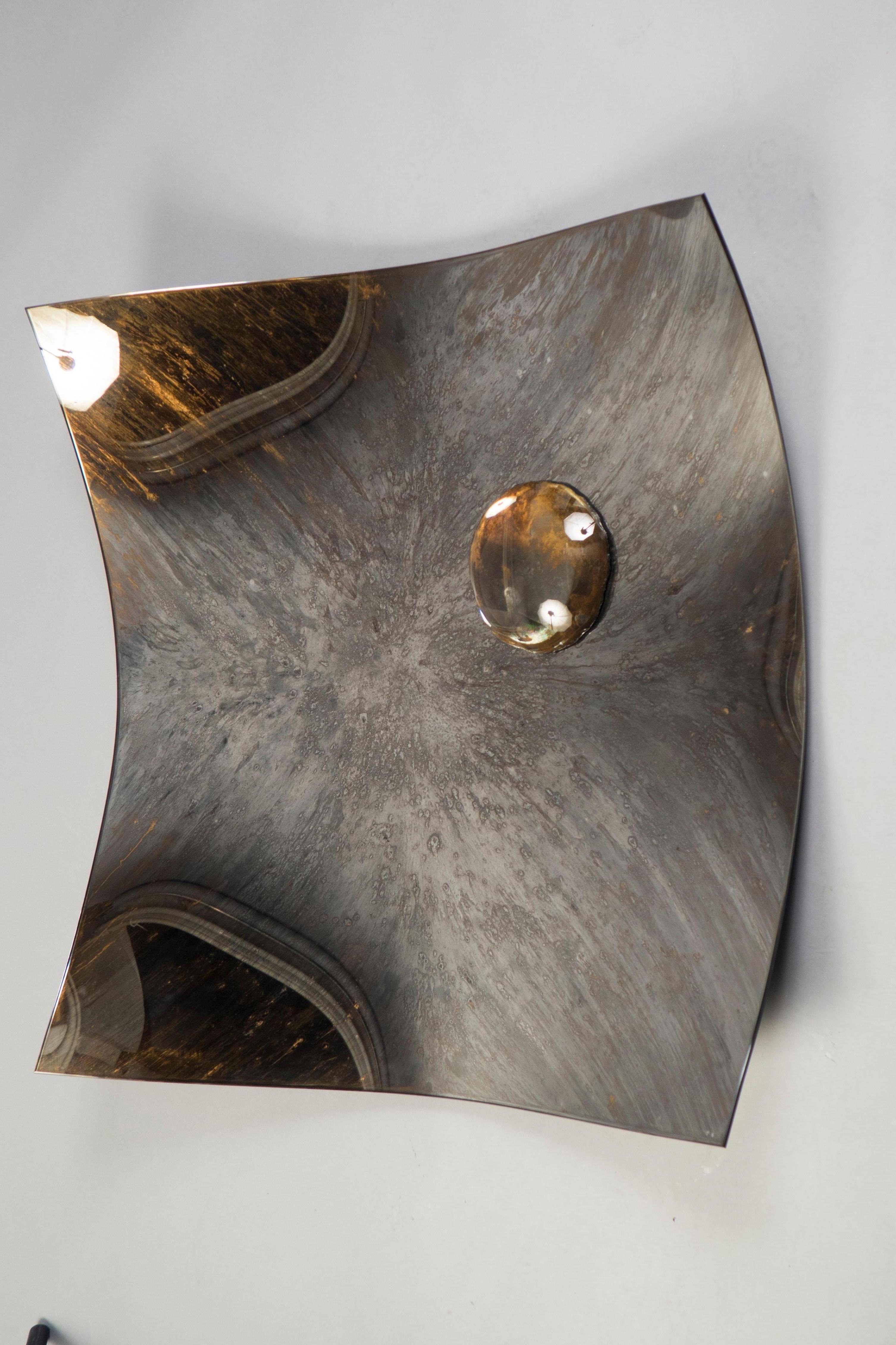 Slightly concave square mirror plate, composed of a gray base color glass with a lighter contrasting color added to create a diffuse-pattern patina. A golden-gray orb rests off-centre.