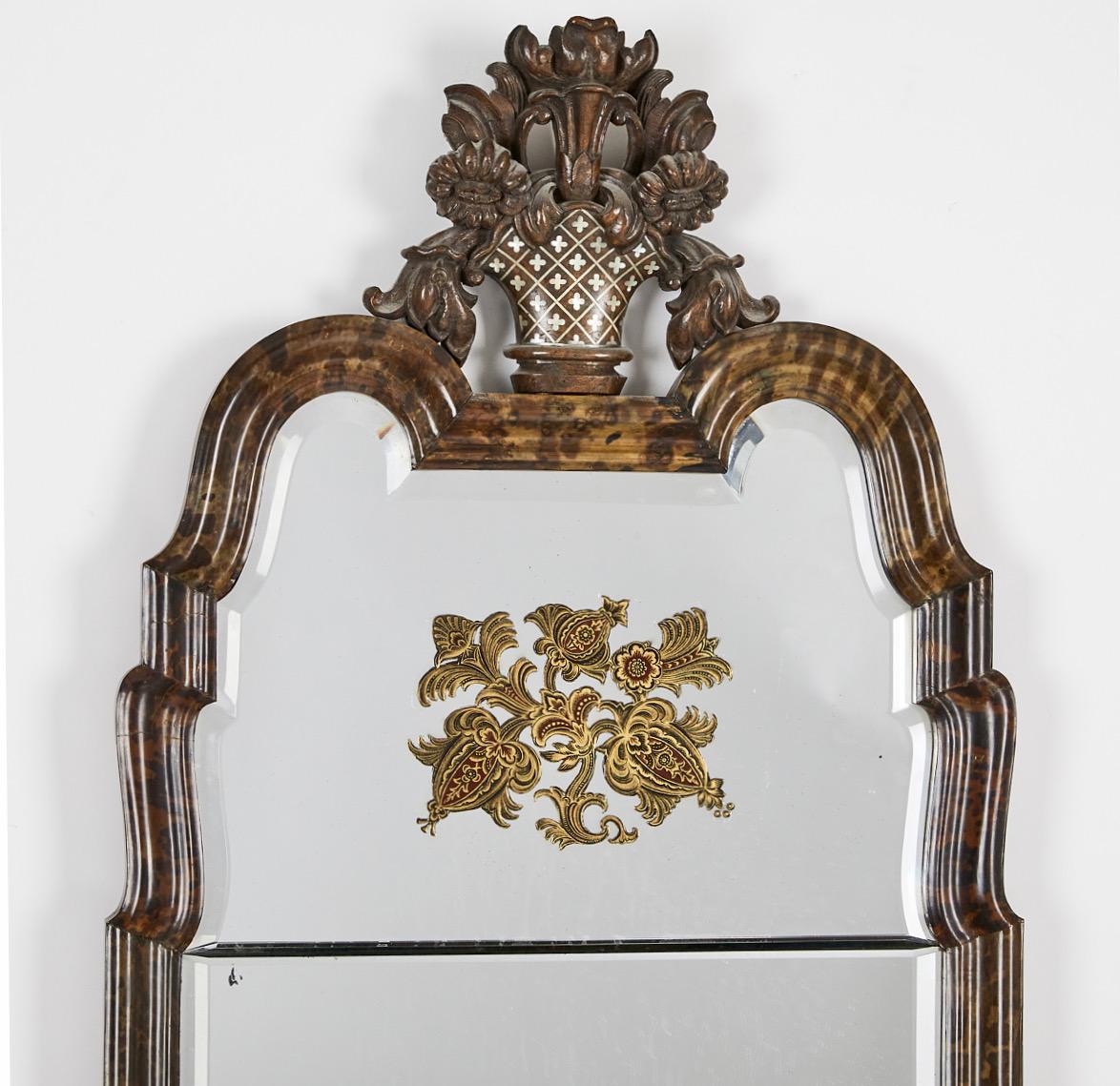 An important Swedish mirror made for The Stockholm Exhibition, 1930 (Stockholmsutställningen). Veneered with tortoise-shell, cut and engraved mirror glass with floral decoration in gold and red, the sculpted top carved in elm root with inlaid pewter