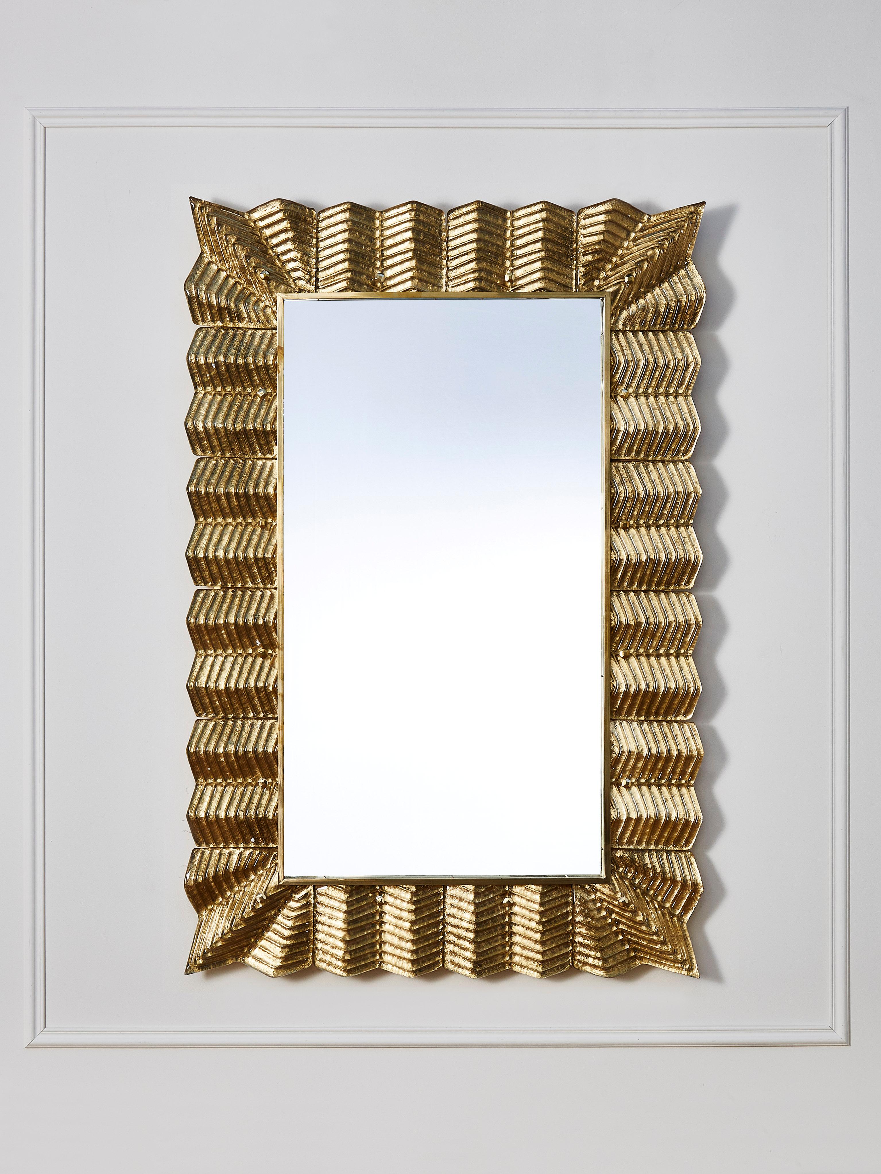 Mirror with a frame made of brass and scilpted Murano glass gilt with gold leaf. 
Creation by Studio Glustin.
Pair available.