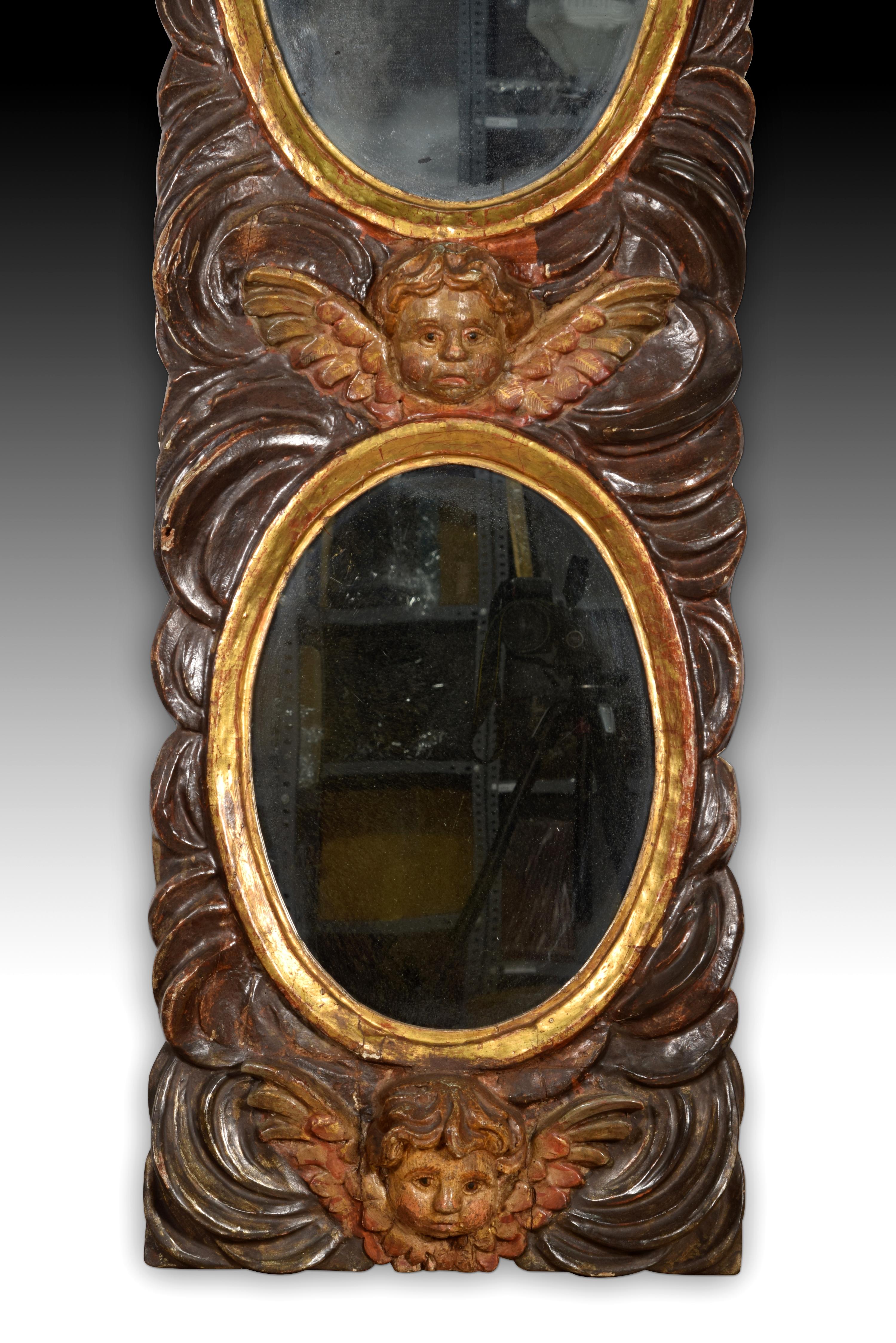 Mirror with angel heads. Carved and polychrome pine wood. Spanish school, 18th century.
 Rectangular panel of carved, polychrome and gilded pinto wood that presents two ovals framed with smooth moldings and topped, each one, with a winged angel head