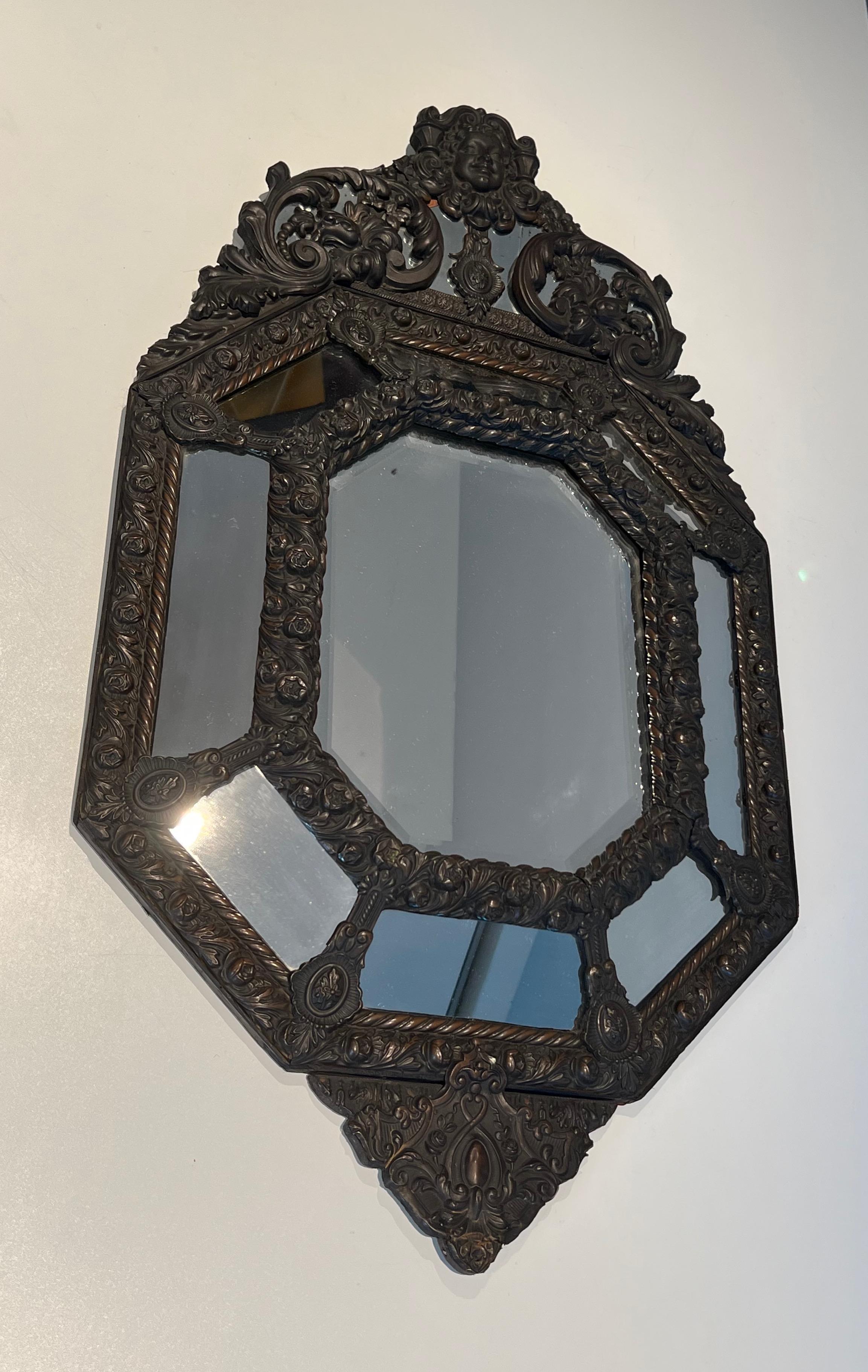 Questo bellissimo e interessante specchio a paresi chiuse è realizzato in specchi e  in rame repoussé, decorato con ghirlande di fiori e sormontato dall'effigie del Re Sole. Si tratta di un'opera francese nello stile di Luigi XIV. Circa 1880,