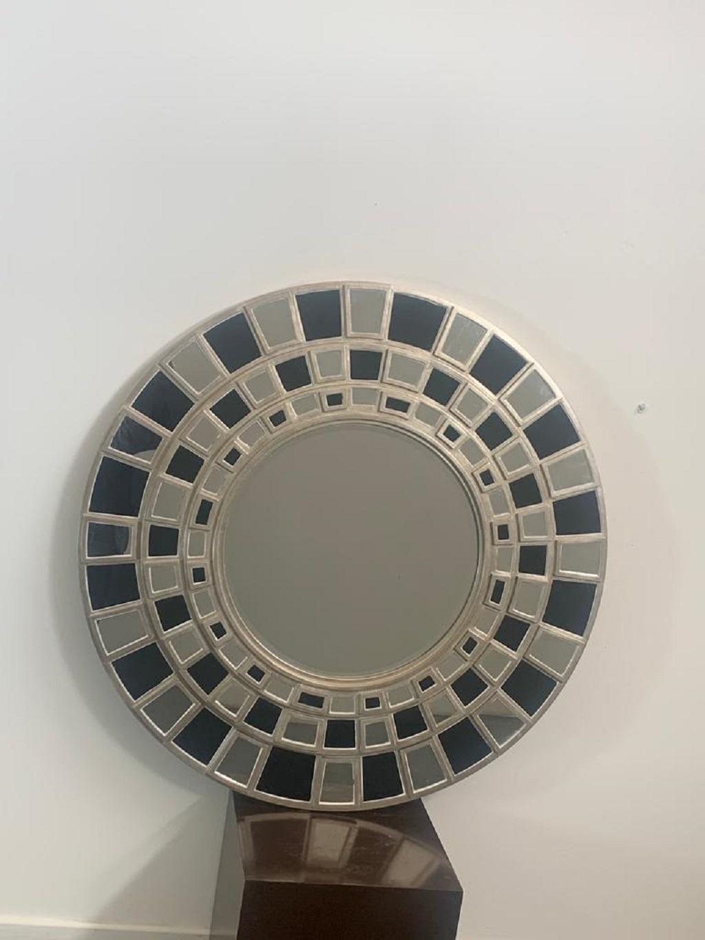 Round wall mirror by Lam Lee Group, 1990s. The frame is on three levels with overlapping black glass and mirror tiles. The structure is made of silver solid wood.
Packaging with bubble wrap and cardboard boxes is included. If the wooden packaging is