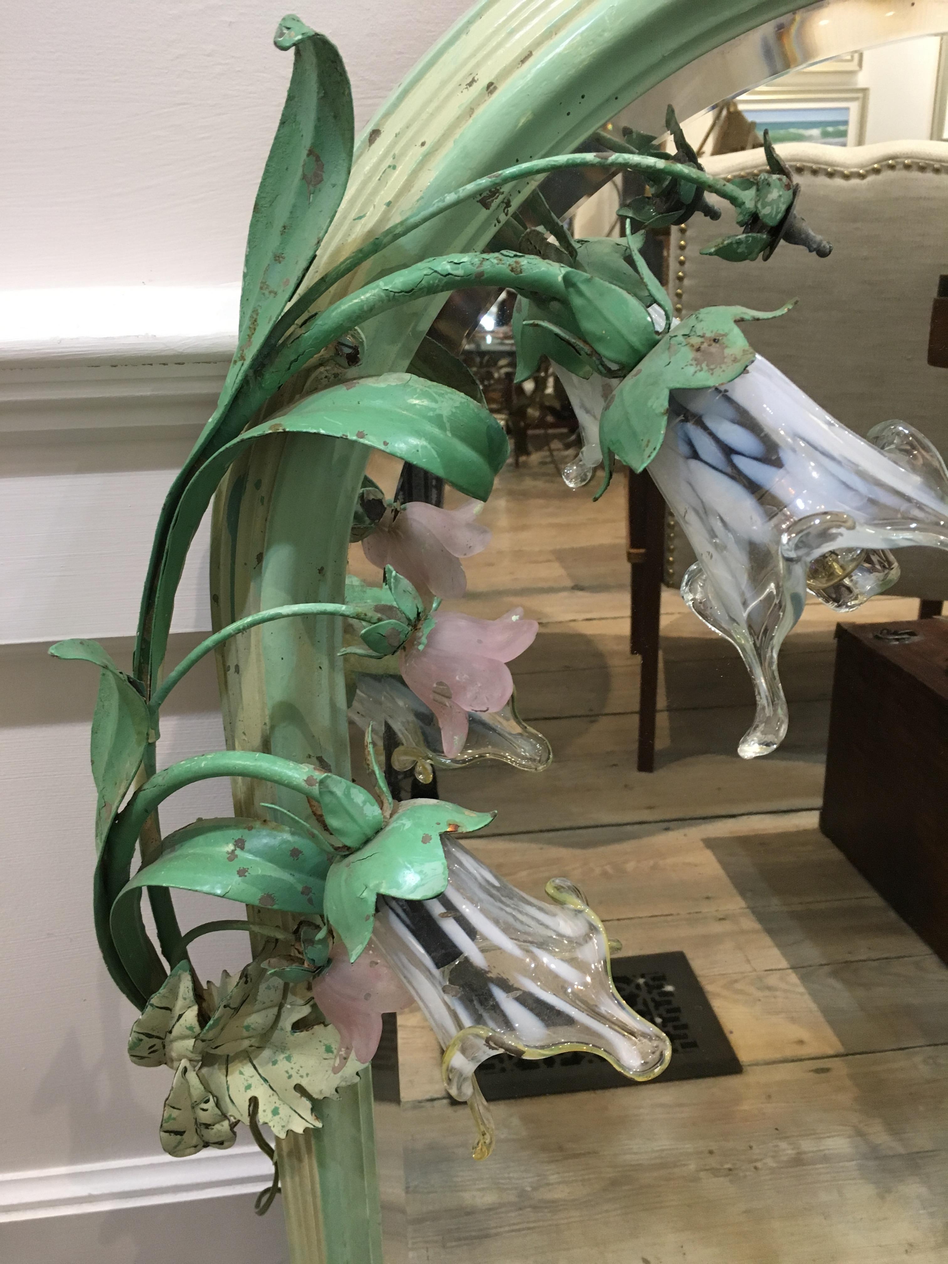 A wood frame mirror with the original green paint with painted iron flower stems with glass flowers, two of which light up. One glass flower is missing, but simply looks like a bud not yet in bloom. This has been rewired and the mirror is beveled. A