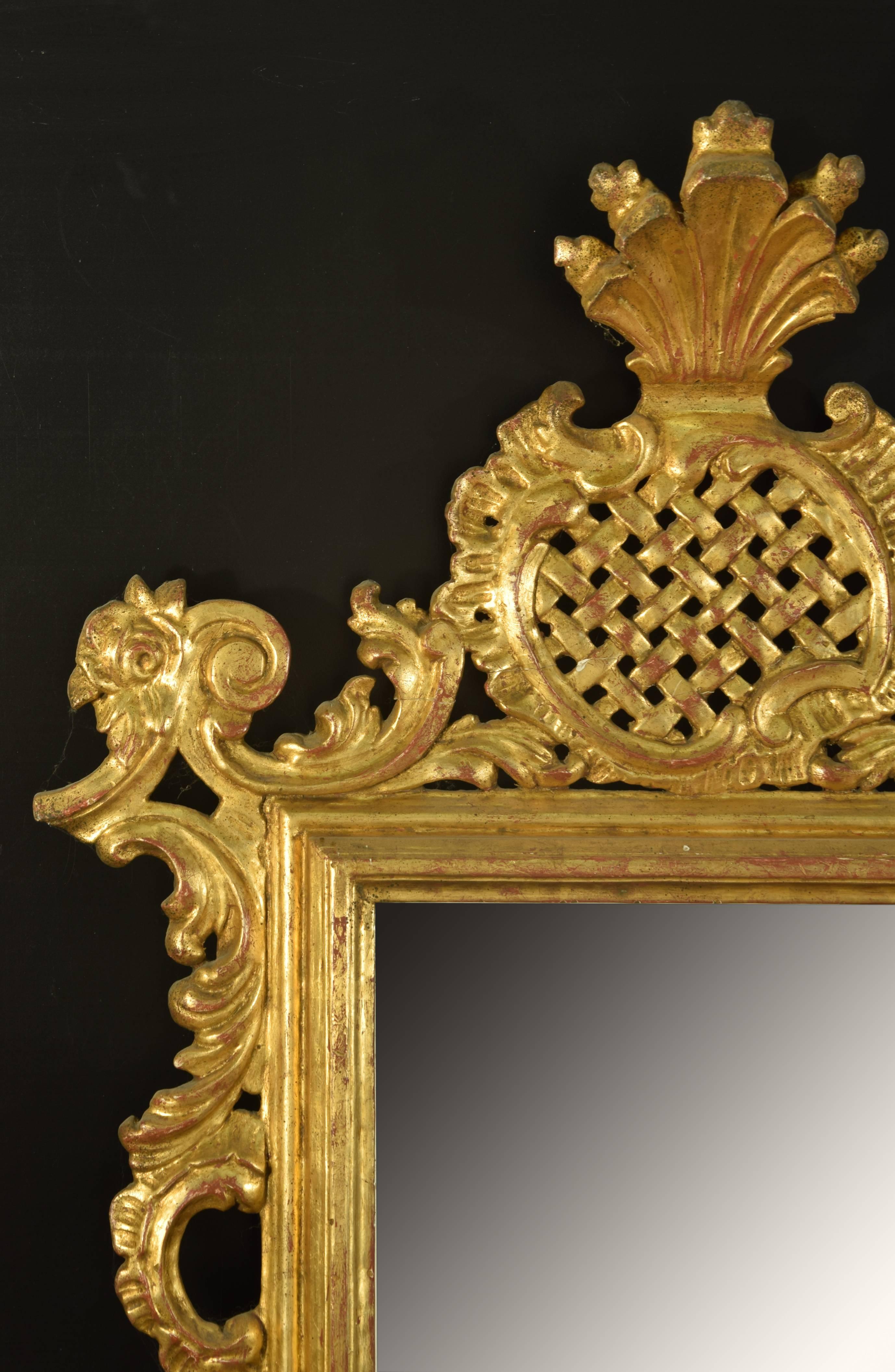 Rectangular mirror highlighted by a decoration based on carved vegetable elements and a motif of bars under a vegetable form. The curves that the leaves draw show the influence of Rococo models for the creation of this work, very softened the
