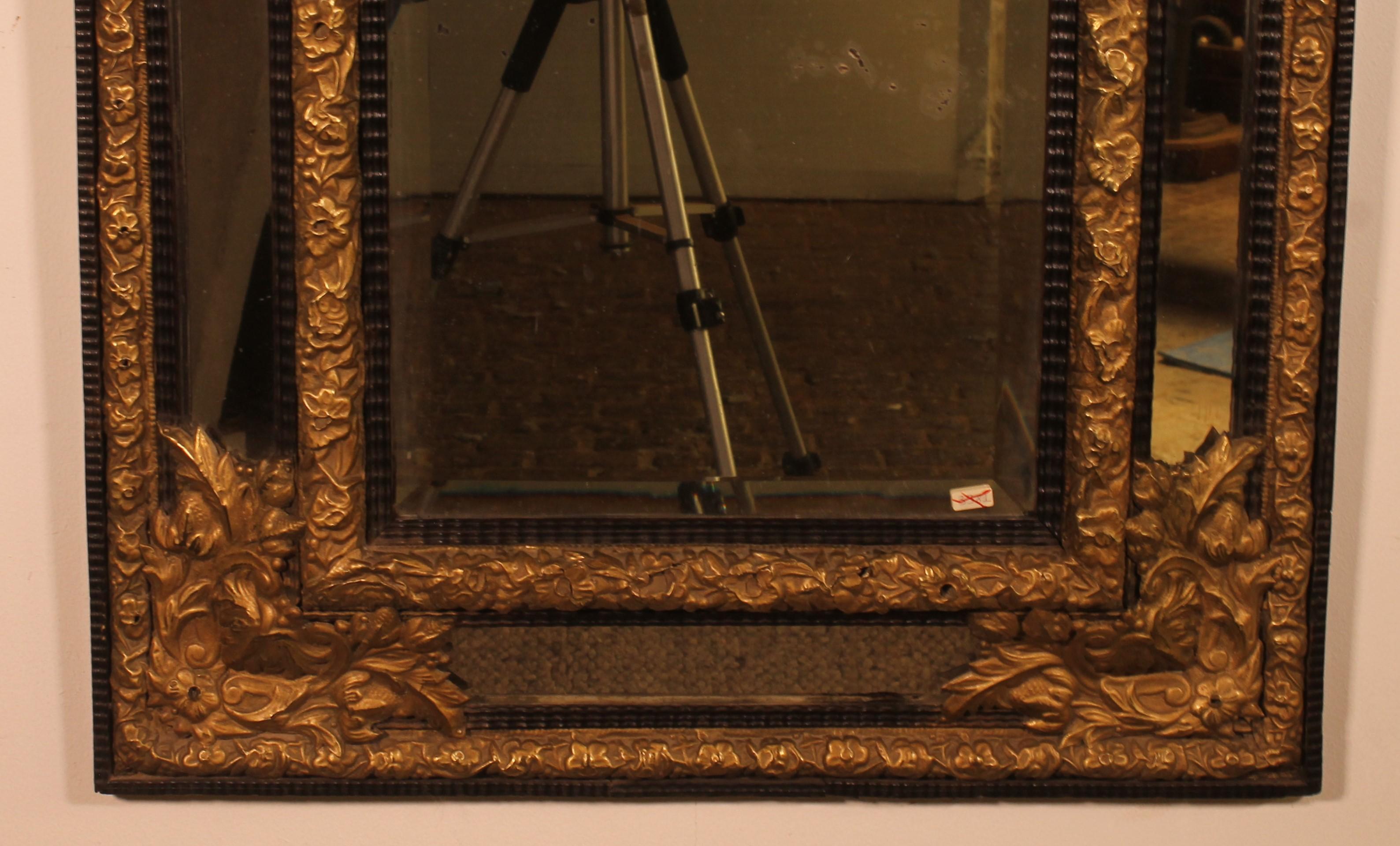 Elegant miroir à parecloses en ébène et cuivre repoussé du début du 19ème siècle.

Très beau miroir de belle proportion décoré de cuivre repoussé et doré au feu et de bois d'ébène.

Il possède sa vitre d'origine en très bon état et qui est