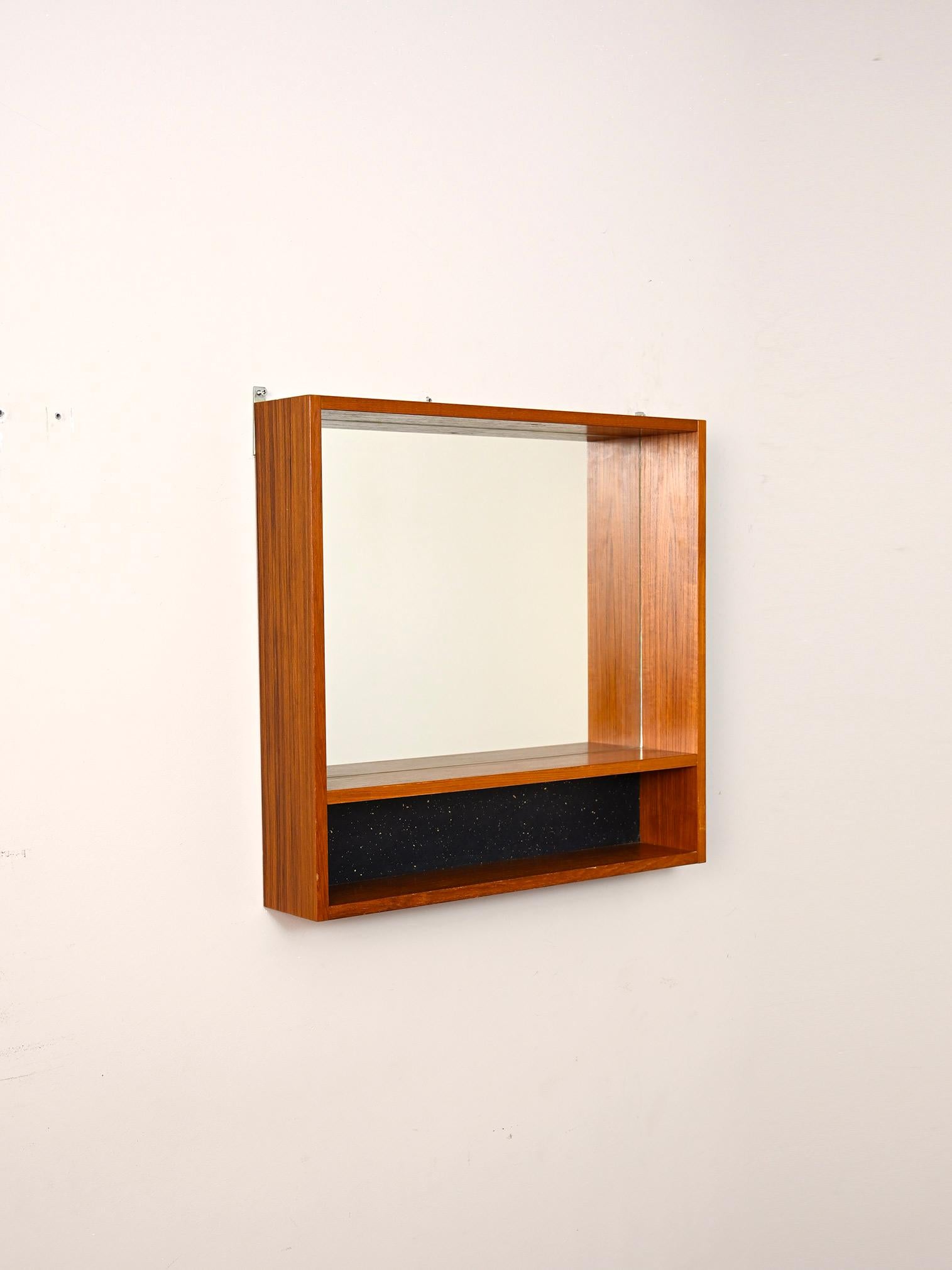 Original 1960s teak framed mirror.

Peculiar piece of vintage Scandinavian modernism with double shelf built into the frame.
Ideal as a mirror to hang above the sink.

Good condition. A conservative restoration has been done. It may show some signs