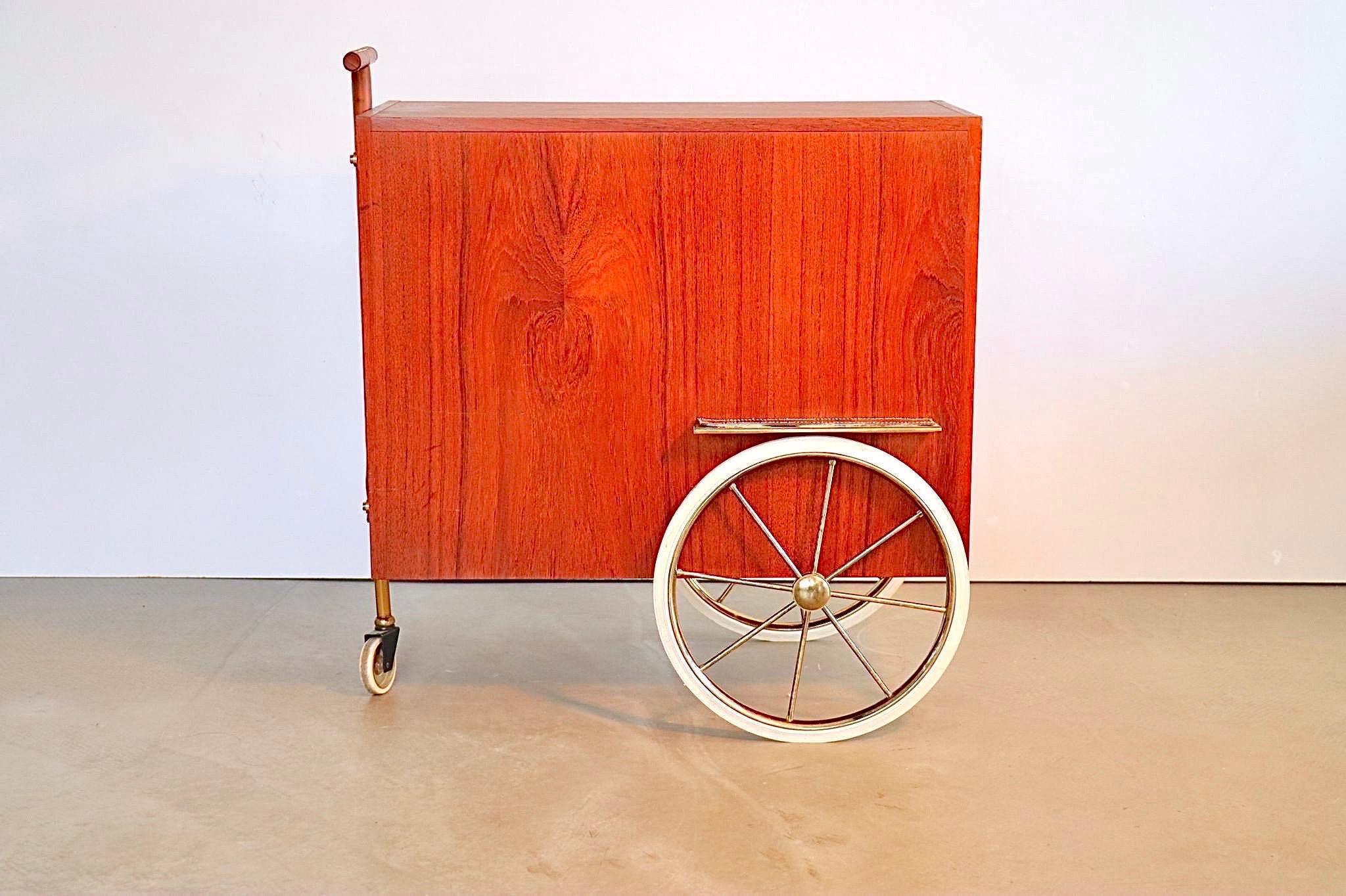 Very elegant oak veneered drinks trolley with in the inside a mirrored bottle compartment, 2 shelves and 6 glass holder clips are mounted to the inside of the door. The doors opens by means of leather handles, the wheel fenders and the steering