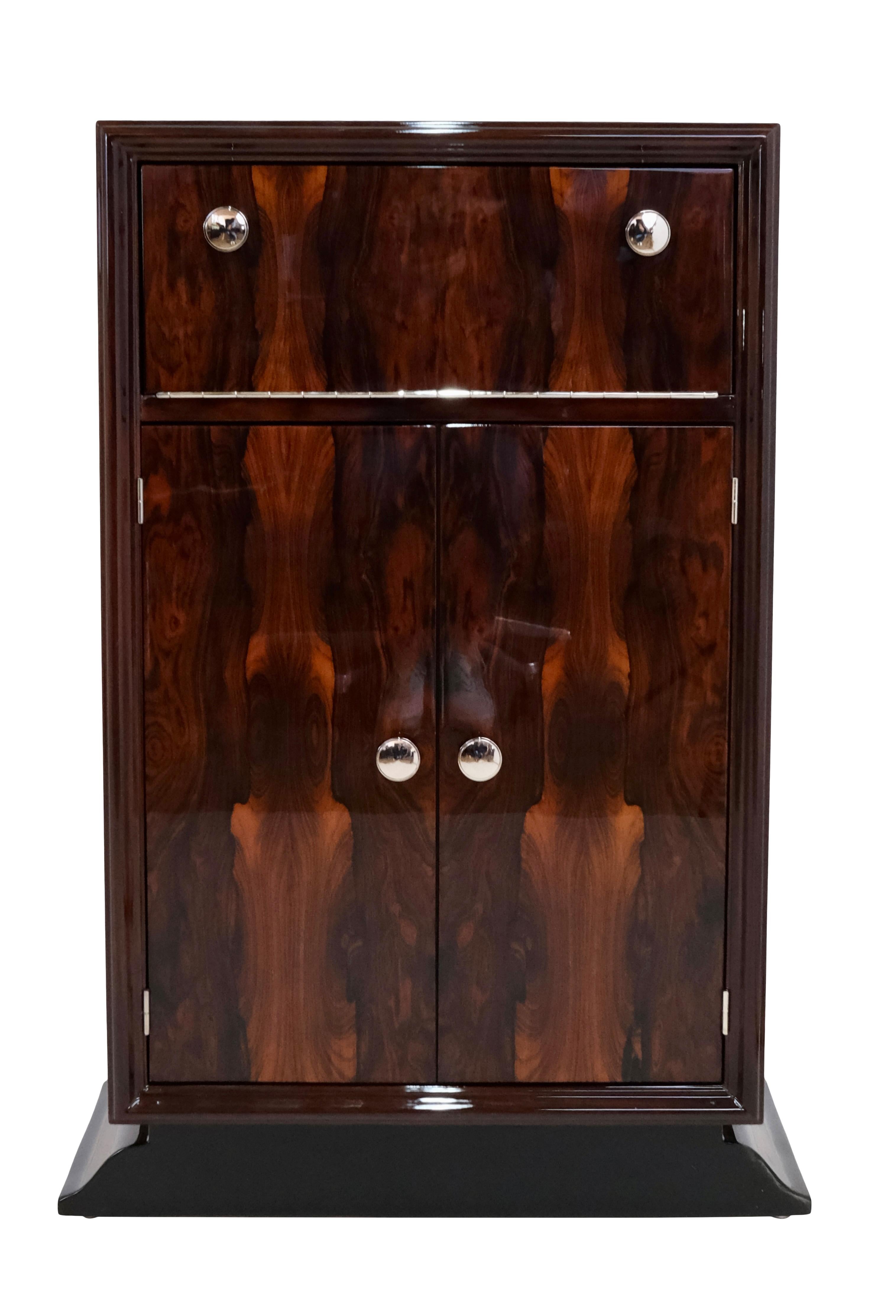 Bar furniture
probably ash veneer, high gloss lacquered
Behind the narrow flap, as well as behind the two doors, a mirrored interior is revealed.

Original Art Deco, France 1930s

Dimensions:
Width: 60 cm
Width, base: 70 cm
Height: 101 cm
Depth: 38