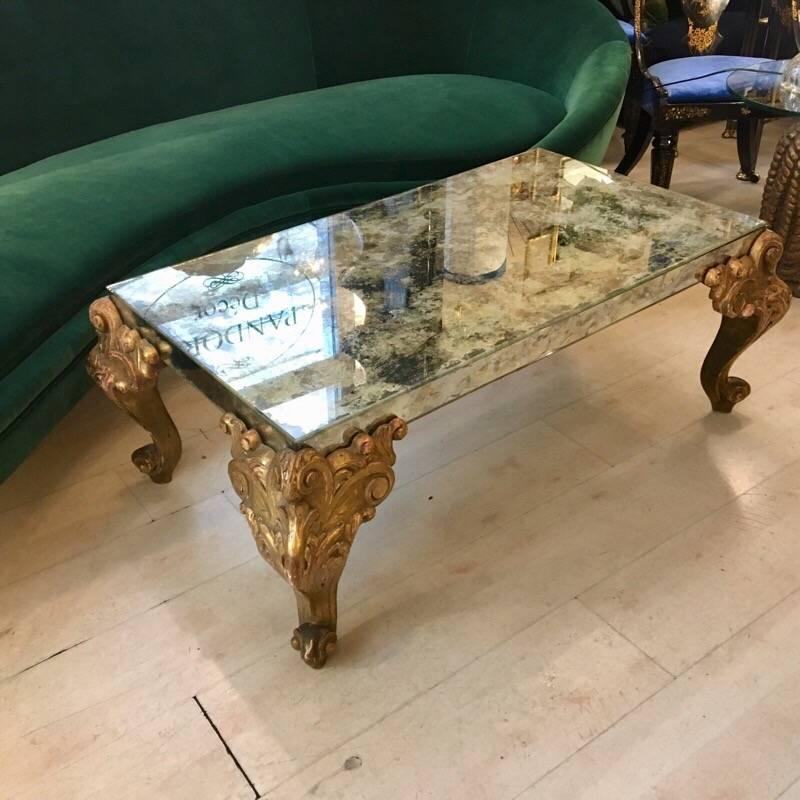 Mirrored glass coffee table with carved wooden gold legs.