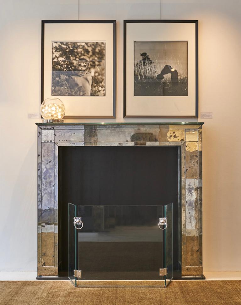 Fireplace clad with a highly patinated mirror with reflections of grey and blue. 
The 19mm plateau and the 10mm framing are made from an extra white 