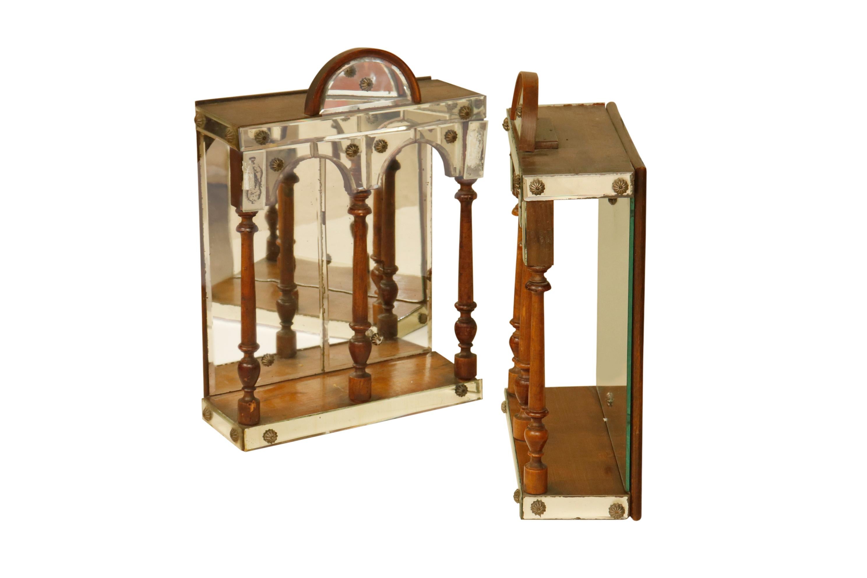 A pair of diminutive hanging wall curio cabinets. Mirrored and embellished in a renaissance Revival style.