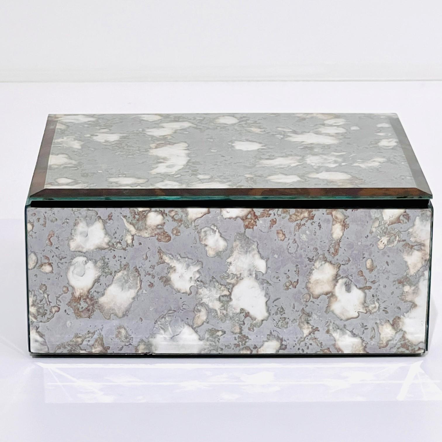 Vintage mirrored decorative box. The glass box captures the beautiful gradient movement of agate stone with antique spotted hues of grey and bronze. The box features beveled edges with a hinged lid and a black velvet felt interior and underside.