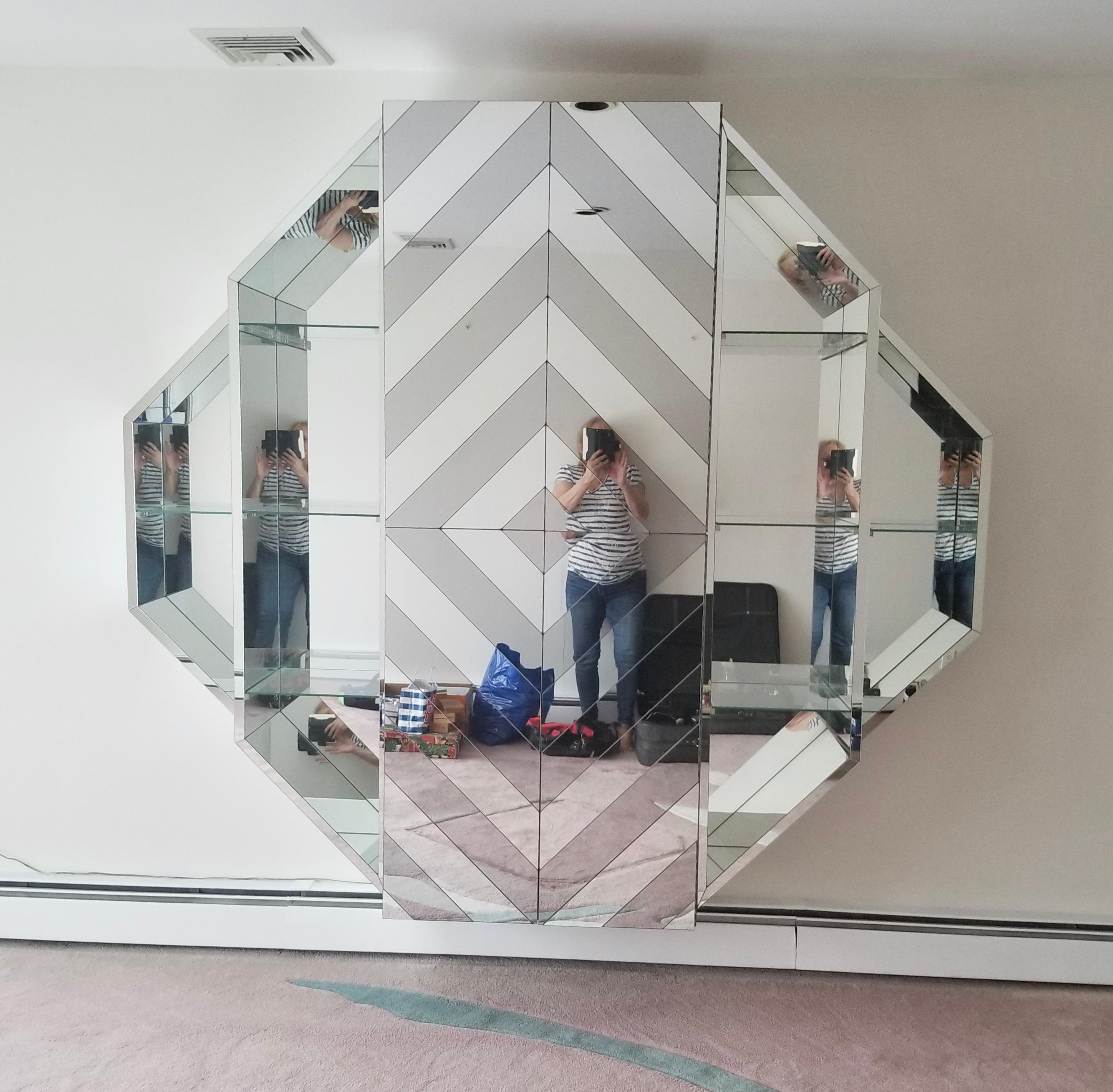 SATURDAY SALE

Custom made wall-mounted octagonal mirrored bar cabinet, circa 1980, USA.

Overall dimensions of this wall unit are 72 inches high by 84 inches wide by 18 inches deep.
It mounts on the wall in five vertical sections with French