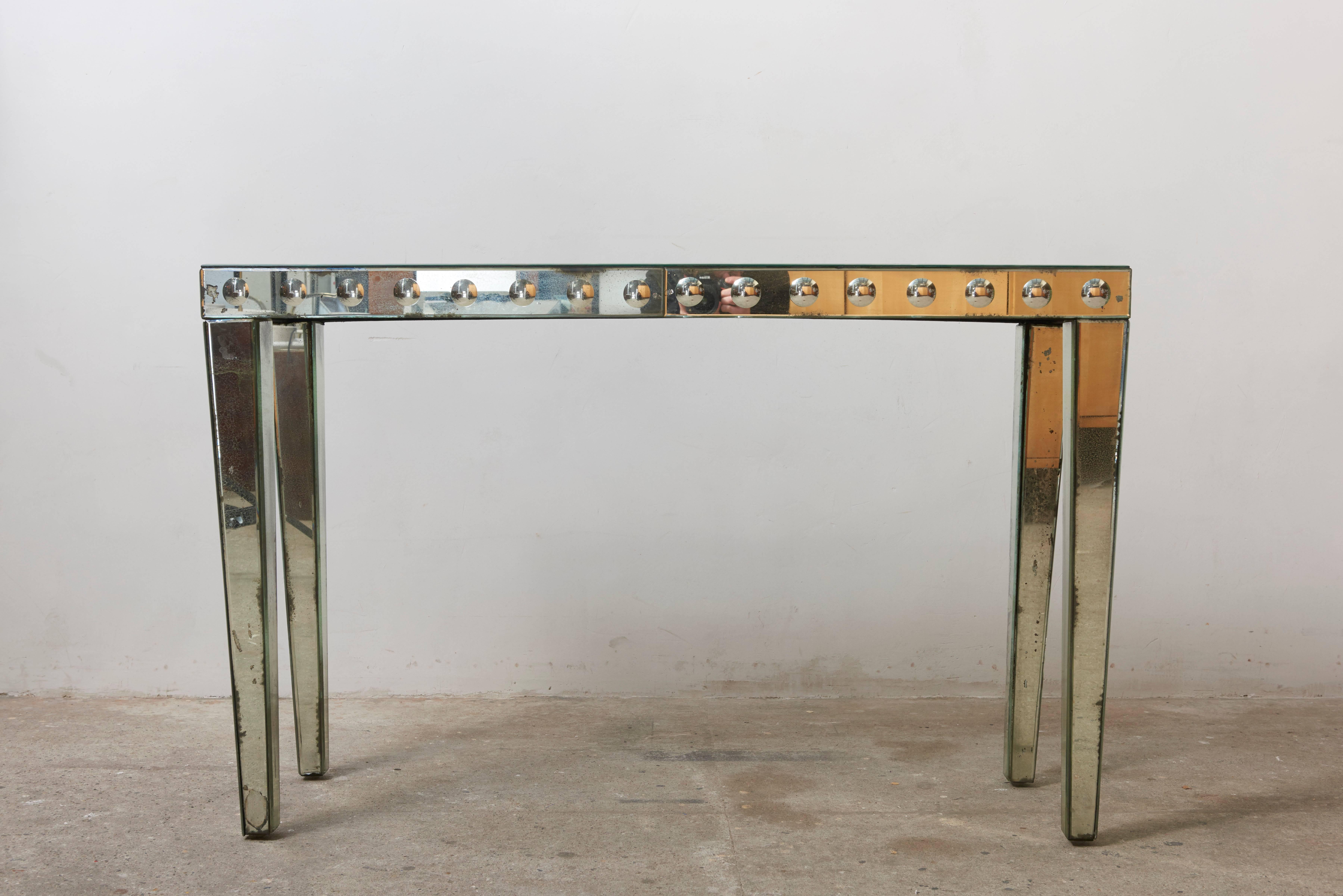 This impressive mirrored console, end-table is made of multiple faceted panels of finished in silver and Églomisé mirror set into a wood table. 


The overall condition is quite nice, with natural intended aging which gives a special