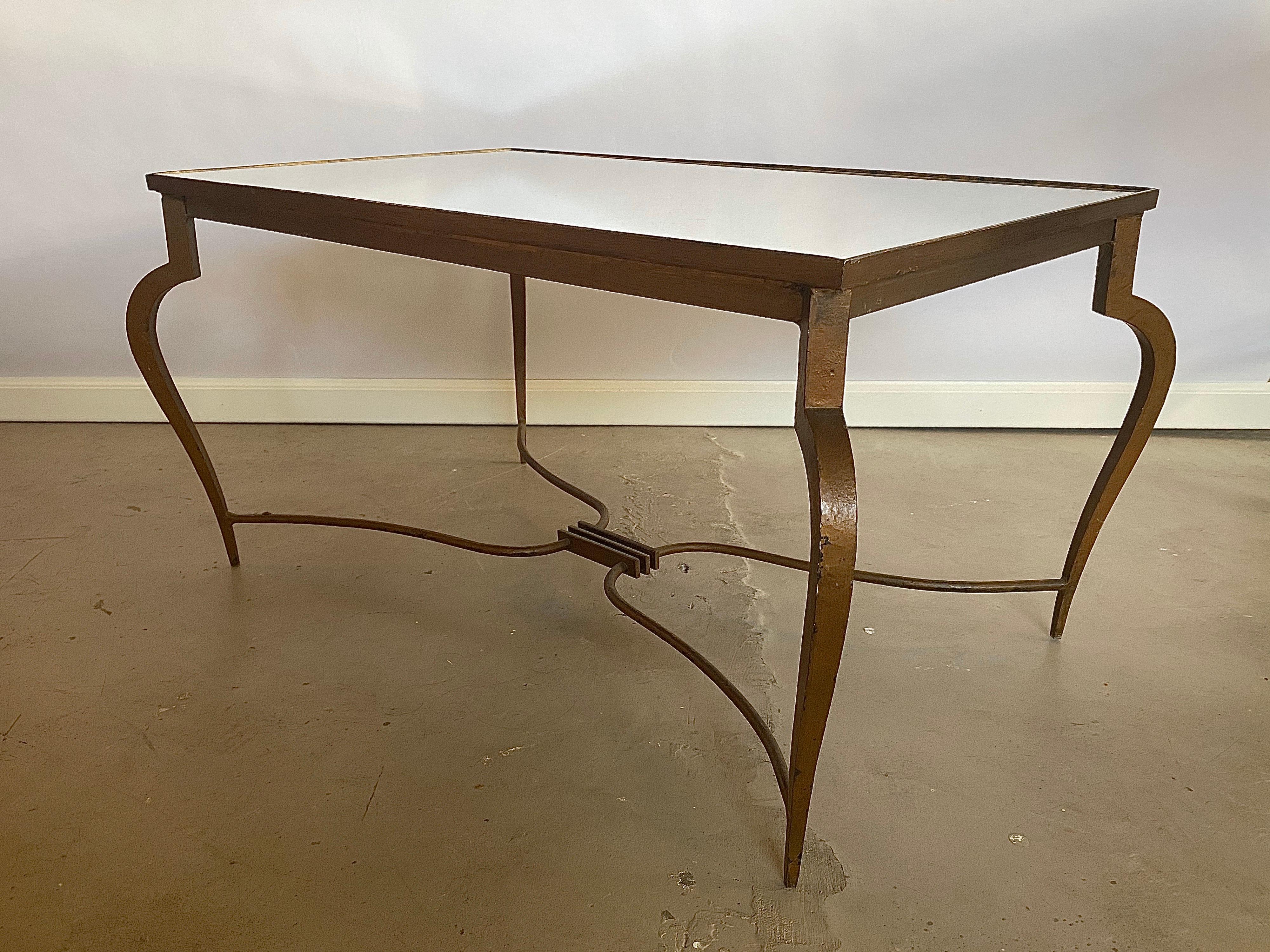 Very elegant coffee table made of wrought iron with a rectangular inset mirror-glass top. Notice the distinguishly bent and curved legs, typical for the 1940s designs of René Prou. The table has a beautifully developed patina over the years which