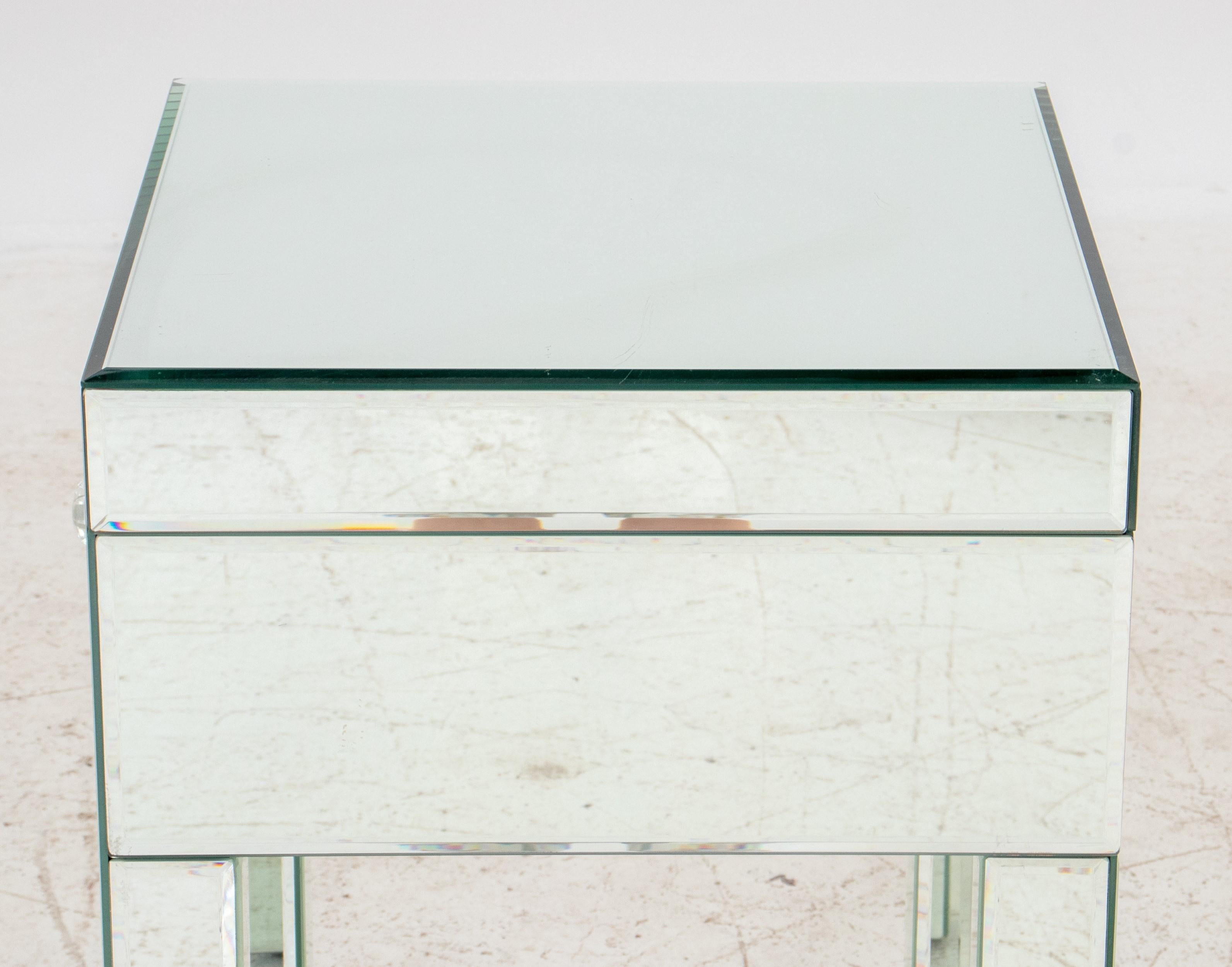  Table d'appoint en miroir, moderne et élégante, avec les caractéristiques suivantes :

Forme : Carré - Le sommet et la base sont de forme carrée.
MATERIAL : Miroir - Toute la surface de la table, y compris la façade des tiroirs, est recouverte de