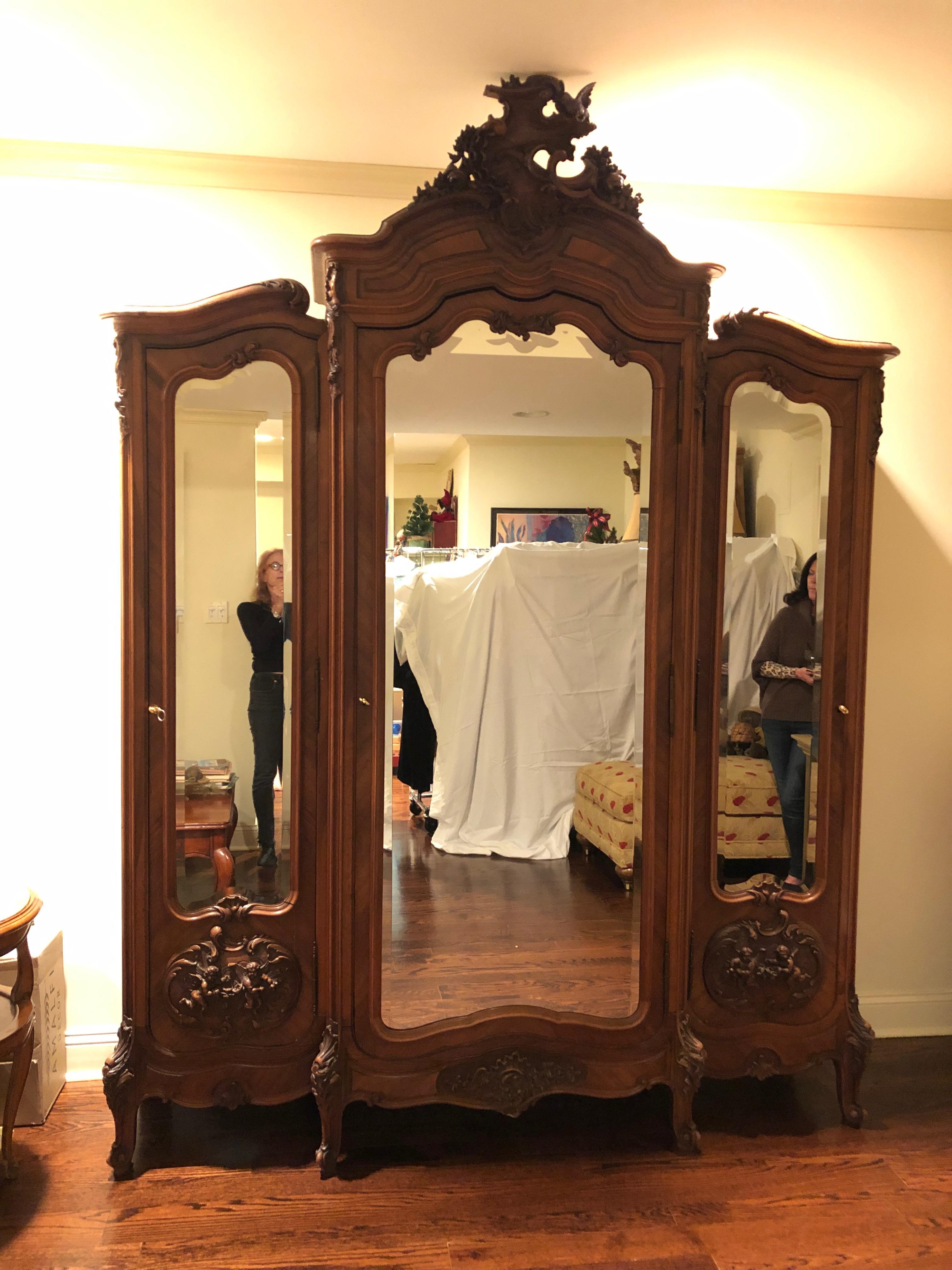 Huge in scale and very impressive Louis XV style 3-part relief carved walnut and walnut veneer parquetry inlaid, beveled mirror armoire, second half of the 20th century, having incredible carved crest able a serpentine moulded cornice, central