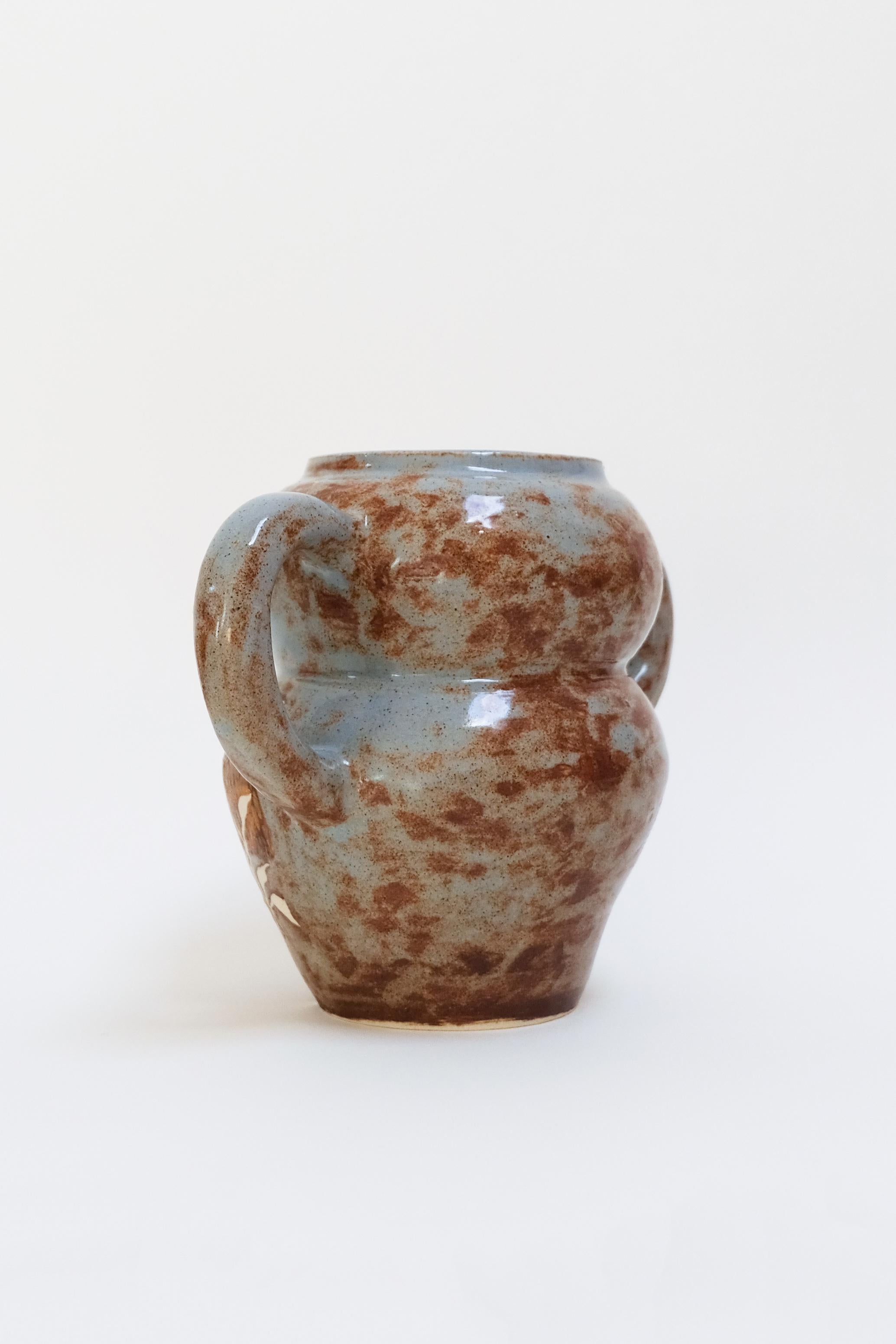 This warm contemporary handled ceramic vase features a unique bird design and is an original artwork by Canadian artist Misbah Ahmed. This piece from her collection of Mur vessels explores organic feminine forms with clay. Mur - meaning curve - uses