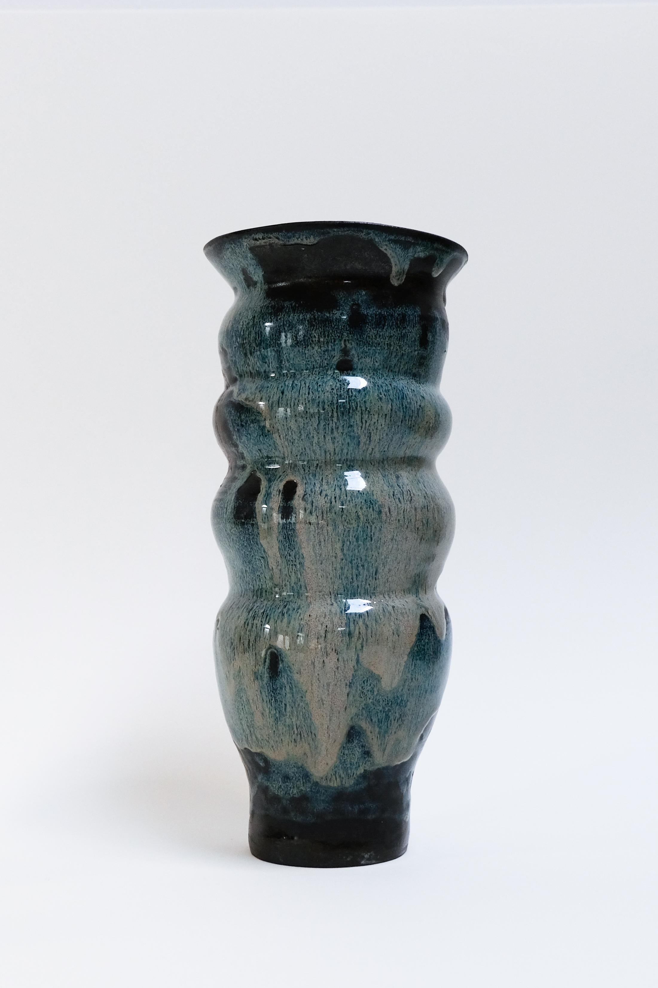 This cool blue contemporary botanical ceramic vase made of black clay is an original artwork by Canadian artist Misbah Ahmed. This piece from her collection of Mur vessels explores organic feminine forms with clay. Mur - meaning curve - uses a