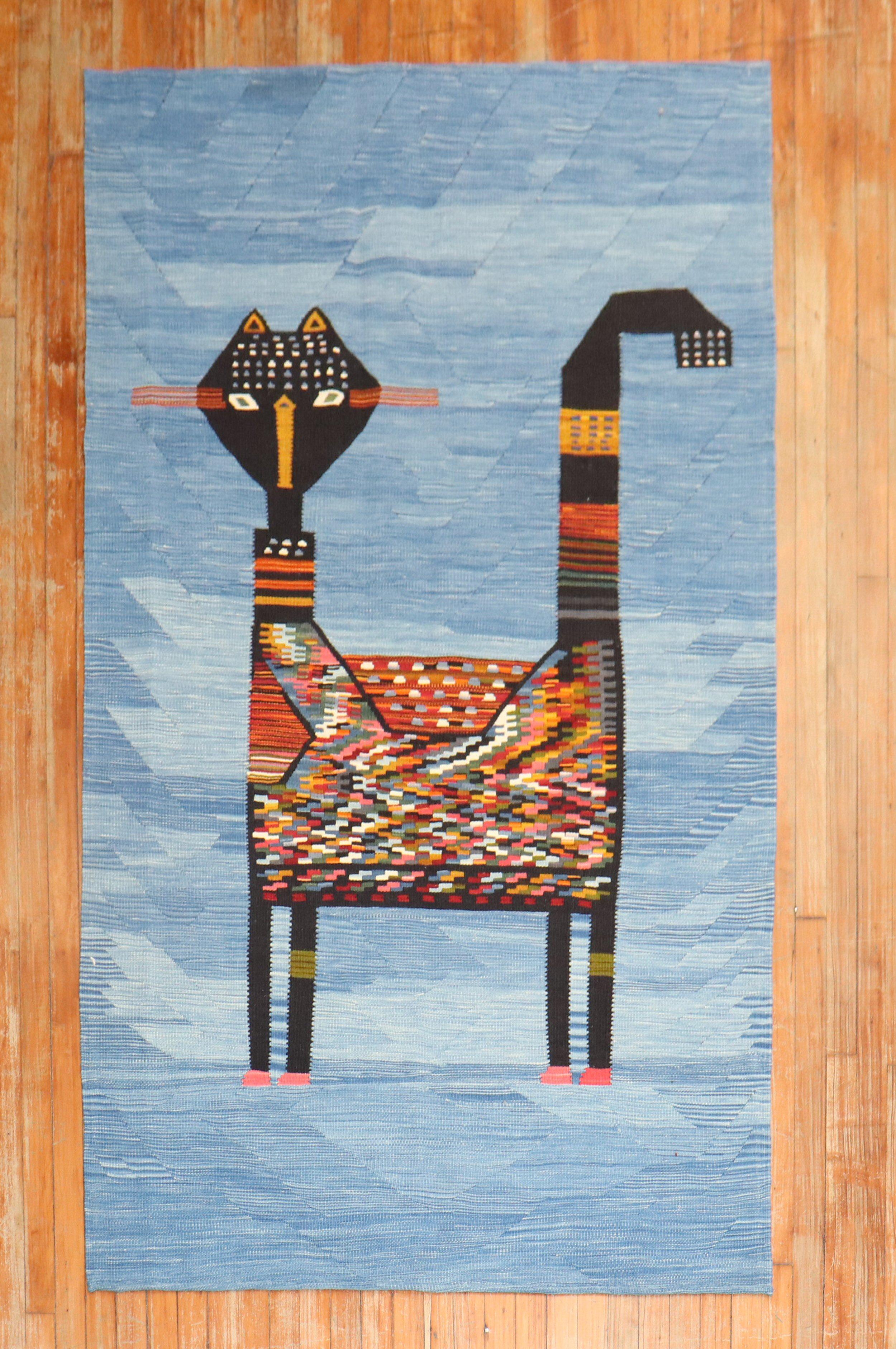 Intermediate-size Persian Kilim from the late 20th century with a large mischievous cat on a light blue field
This was originally belonging to a private Persian collector who requested to make a custom collection of flat-weaves with quirky themes