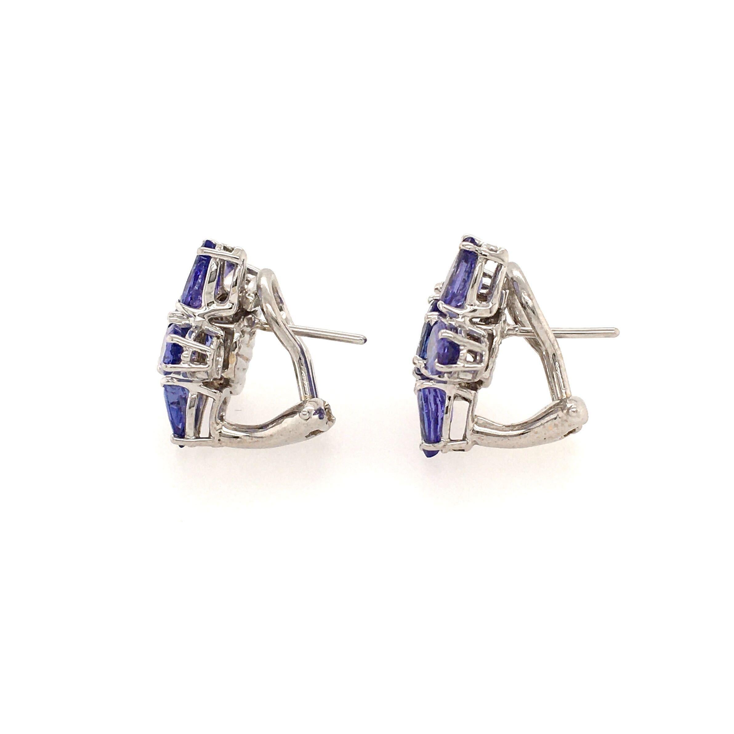 A pair of 18 karat white gold and tanzanite earrings. Mish. Designed as a flower head, centering a circular cut tanzanite, measuring approximately 6.0mm,  extending pear shaped tanzanite petals, measuring approximately 6.0 x 4.0mm. Diameter is