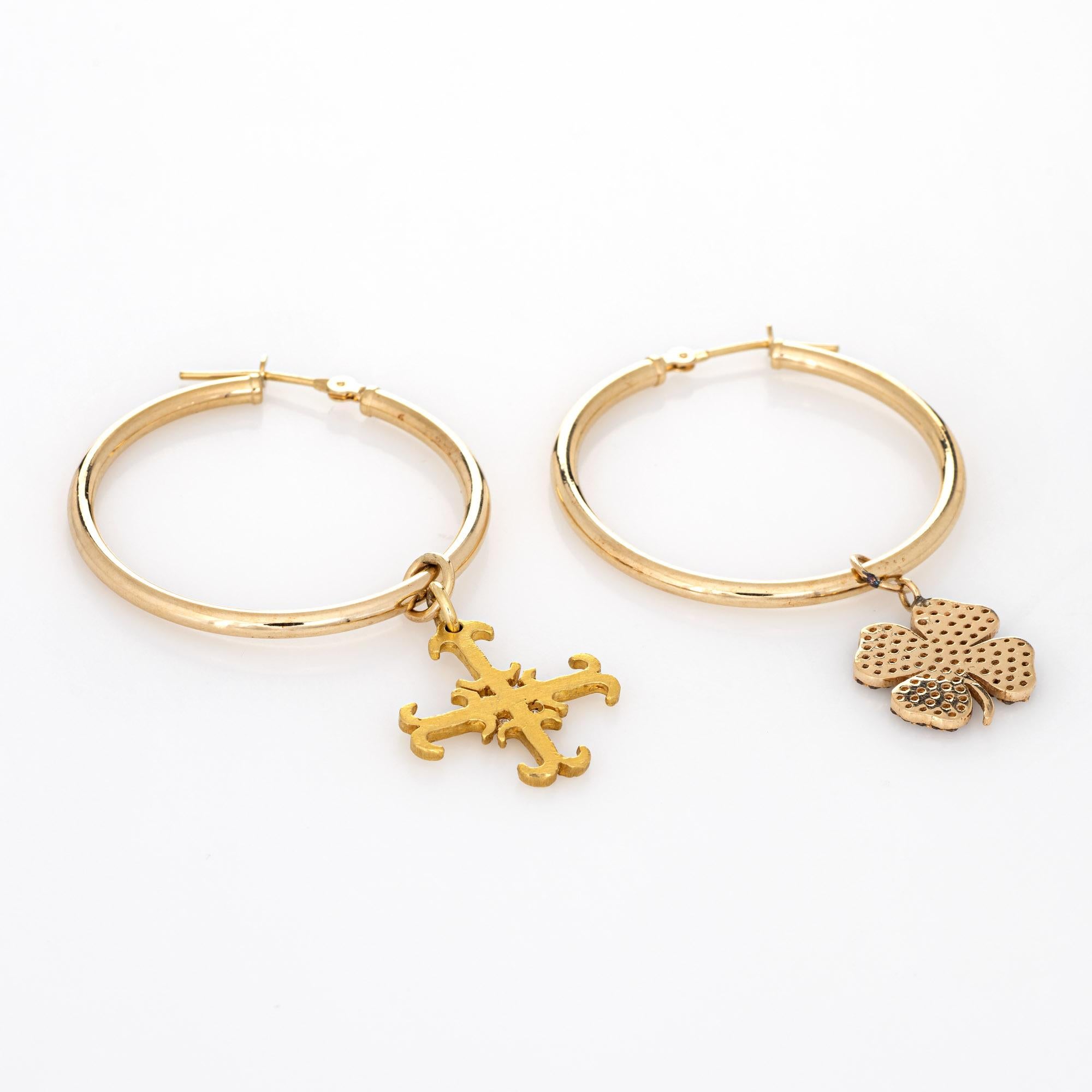 Style pair of mismatched diamond hoop earrings crafted in 14k yellow gold. 

The four leaf clover is set with an estimated 0.40 carats of diamonds (estimated at M-N color and SI2-I1 clarity). The cross is set with an estimated 0.04 carats of