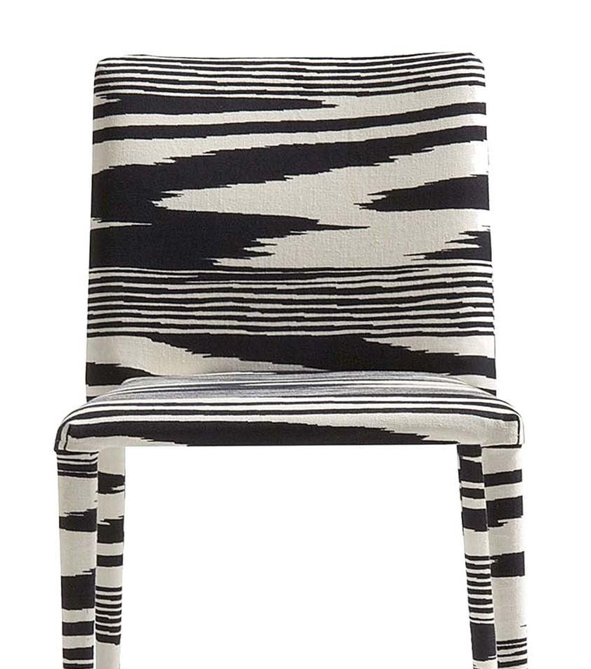 Completely upholstered from top to bottom, this chair's captivating exterior conceals a sturdy construction of steel padded with multi-density expanded polyurethane. Featuring a stackable design with squared seat and back on tapered legs, this chair