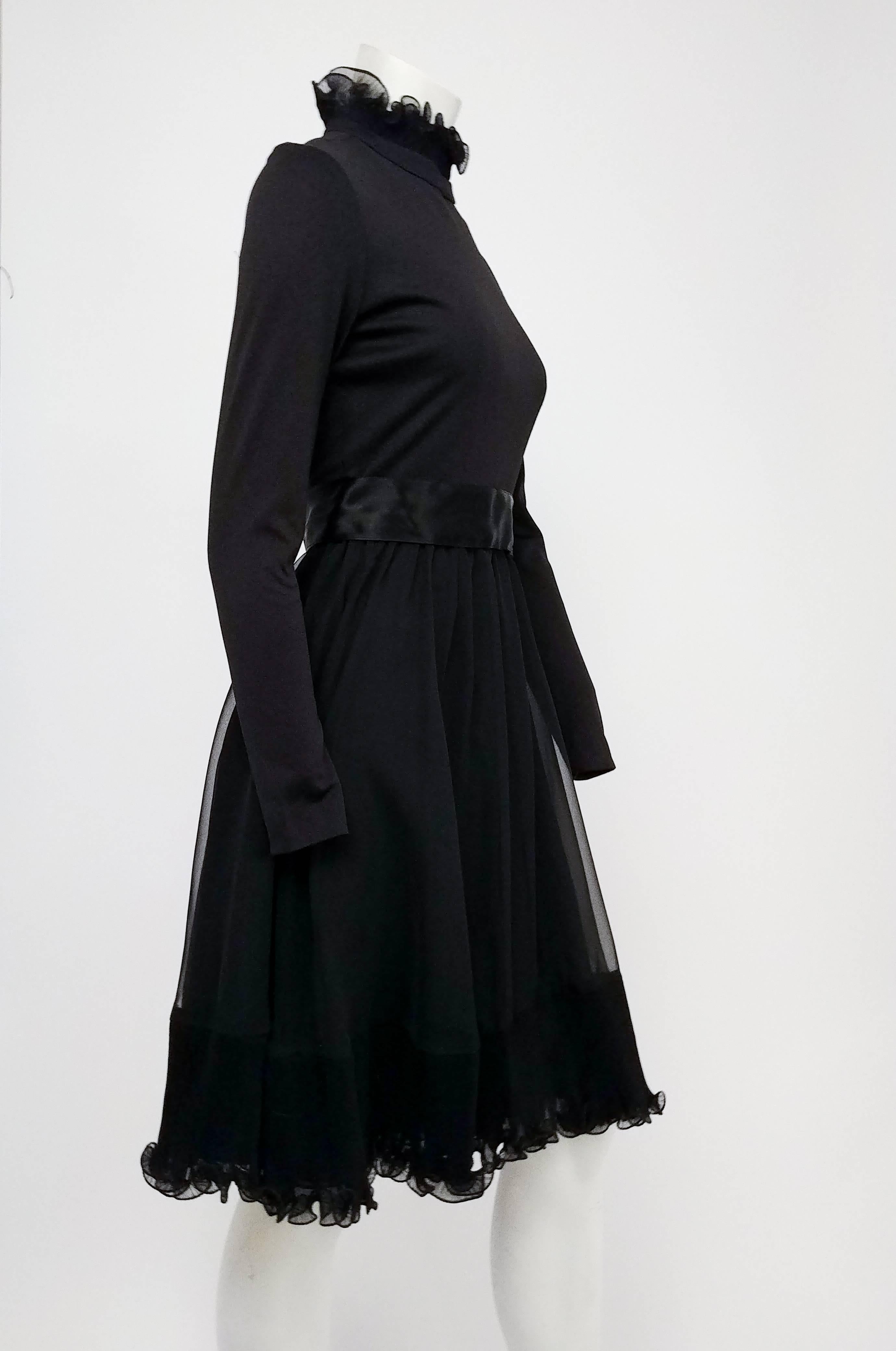 Black Cocktail Dress w/ Ruffled Skirt, 1960s. Elegant high collar with set pleated ruffles matches pleated ruffle trim at hem. Jersey knit bodice, satin belt hooks at back. Slightly flared skirt gives off a feminine, whimsical silhouette. 