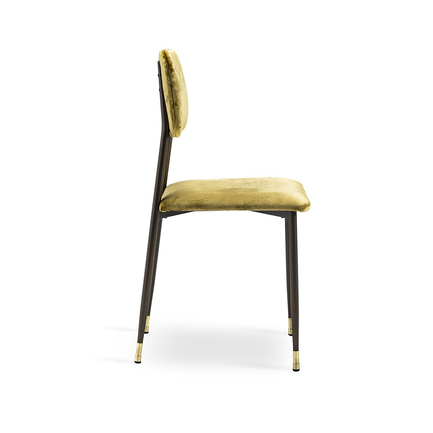 Sunny, bright with a bit of vintage class, this dining chair rests on a slight metal frame and legs that are painted in a brushed bronze finish, with the legs decorated with brass chair guides. The simple but comfortable back and seat, structured