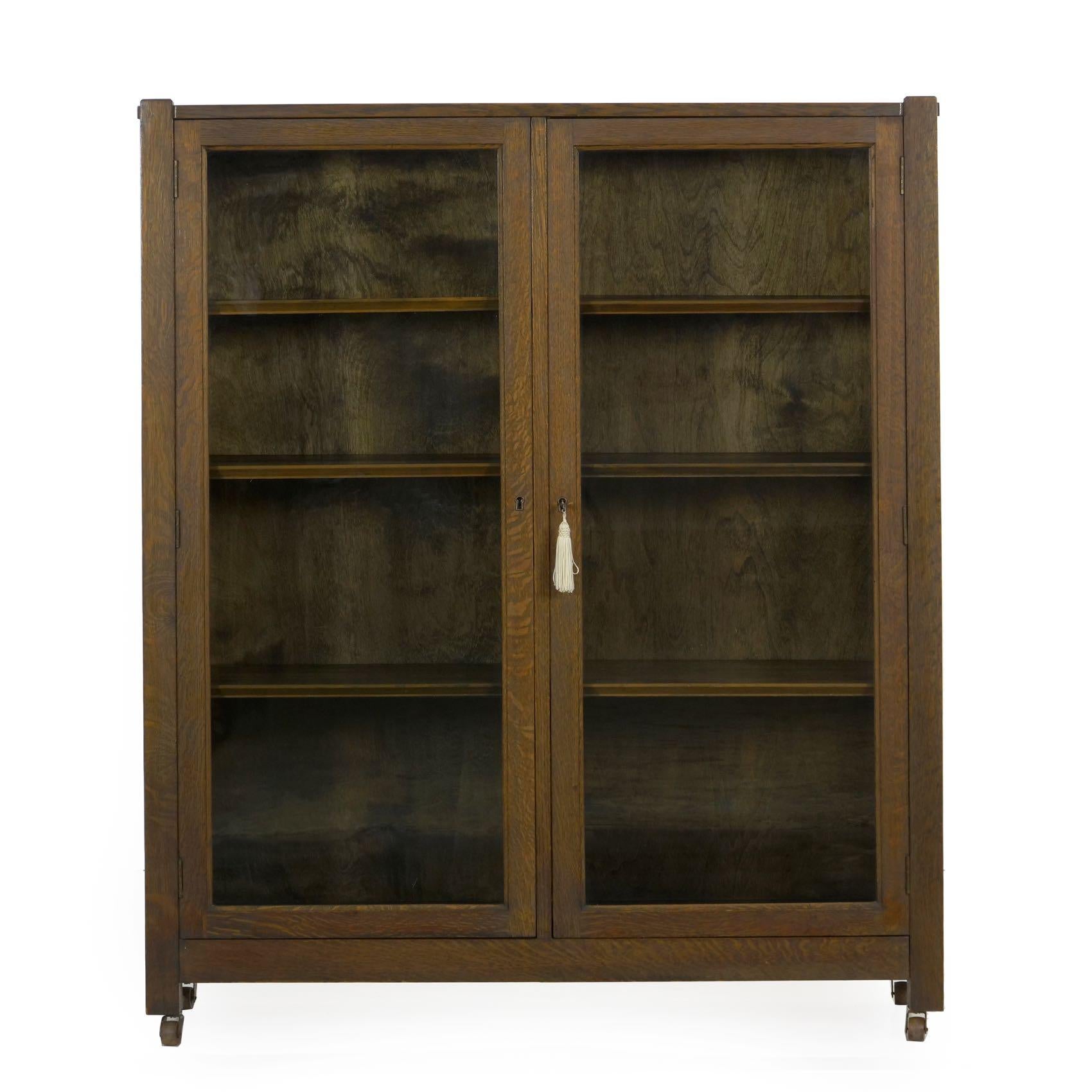 This well constructed cabinet is typical of the period, a tidy and austere form that highlights the beautiful quarter-sawn oak. The pair of hinged doors swing outward to give access to three shelves on either side. One glass pane is replaced while