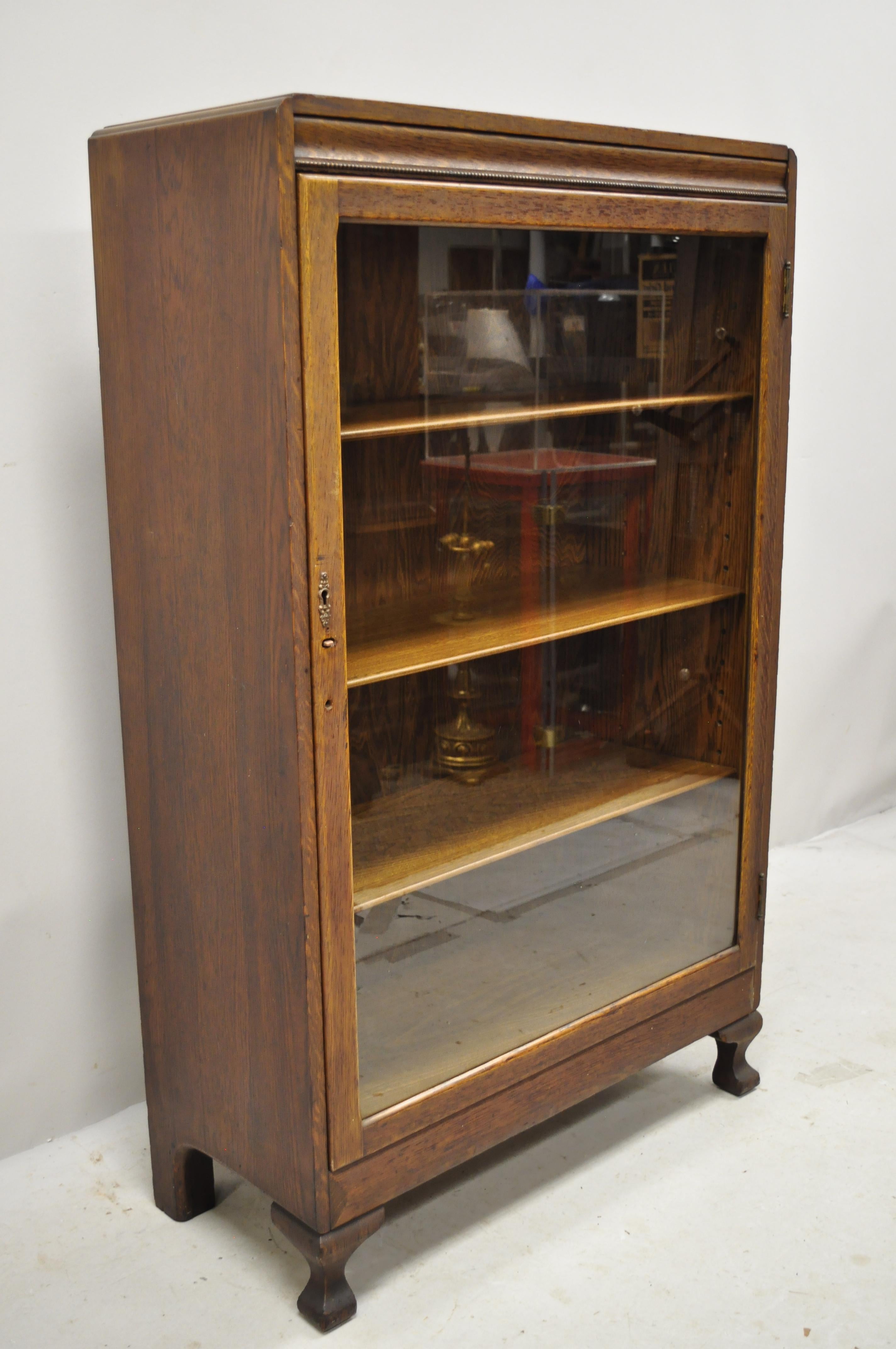 Antique mission Arts & Crafts oakwood single glass door small bookcase display cabinet. Item features solid wood construction, beautiful wood grain, 1 glass swing door, no key, but unlocked, 3 adjustable shelves, very nice antique item, circa early