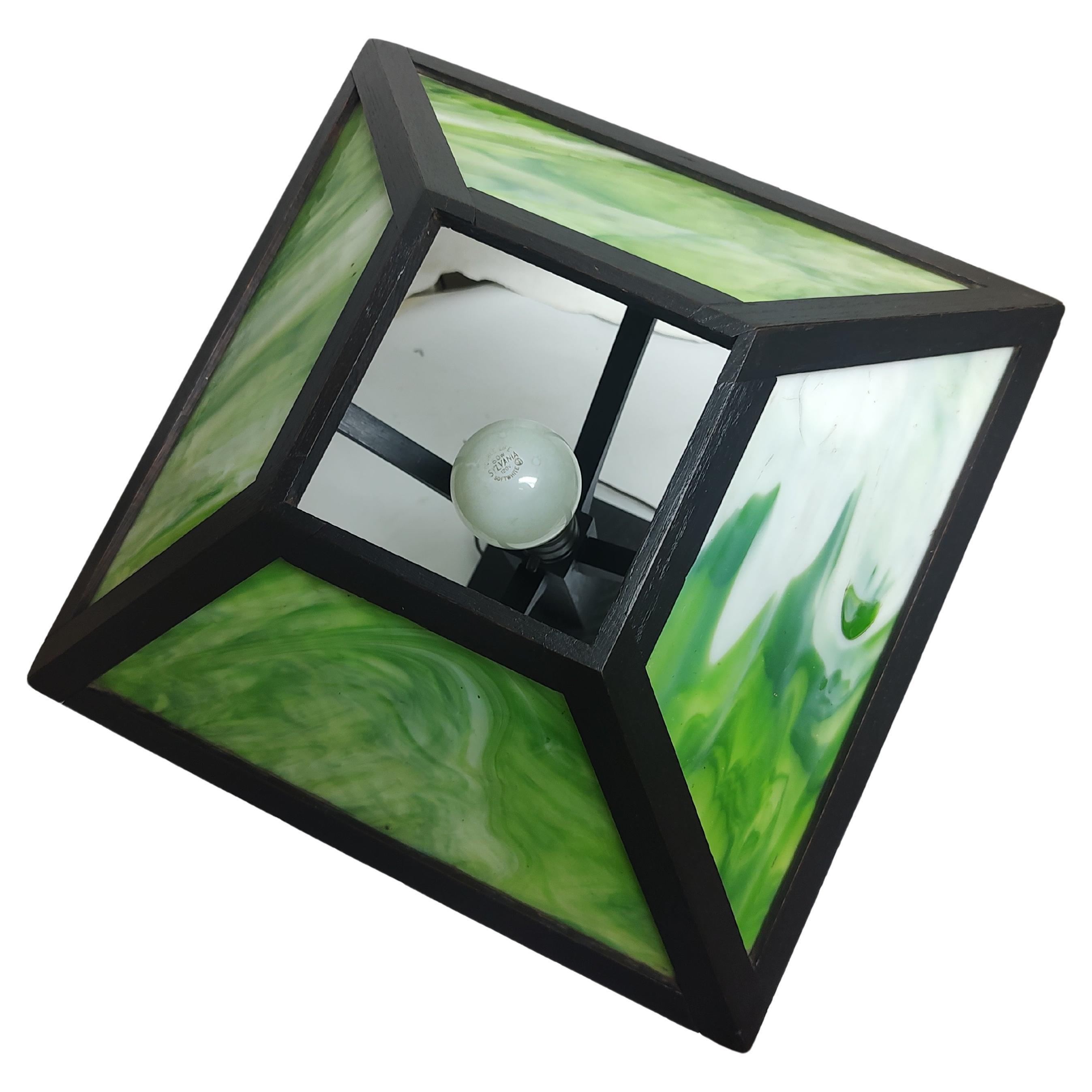 Los bonitos paneles de vidrio verde Slag Glass desprenden un encantador y cálido resplandor cuando están encendidos. La lámpara de C1912 está en excelentes condiciones de antigüedad y se ha repintado recientemente con un tinte oscuro de roble de