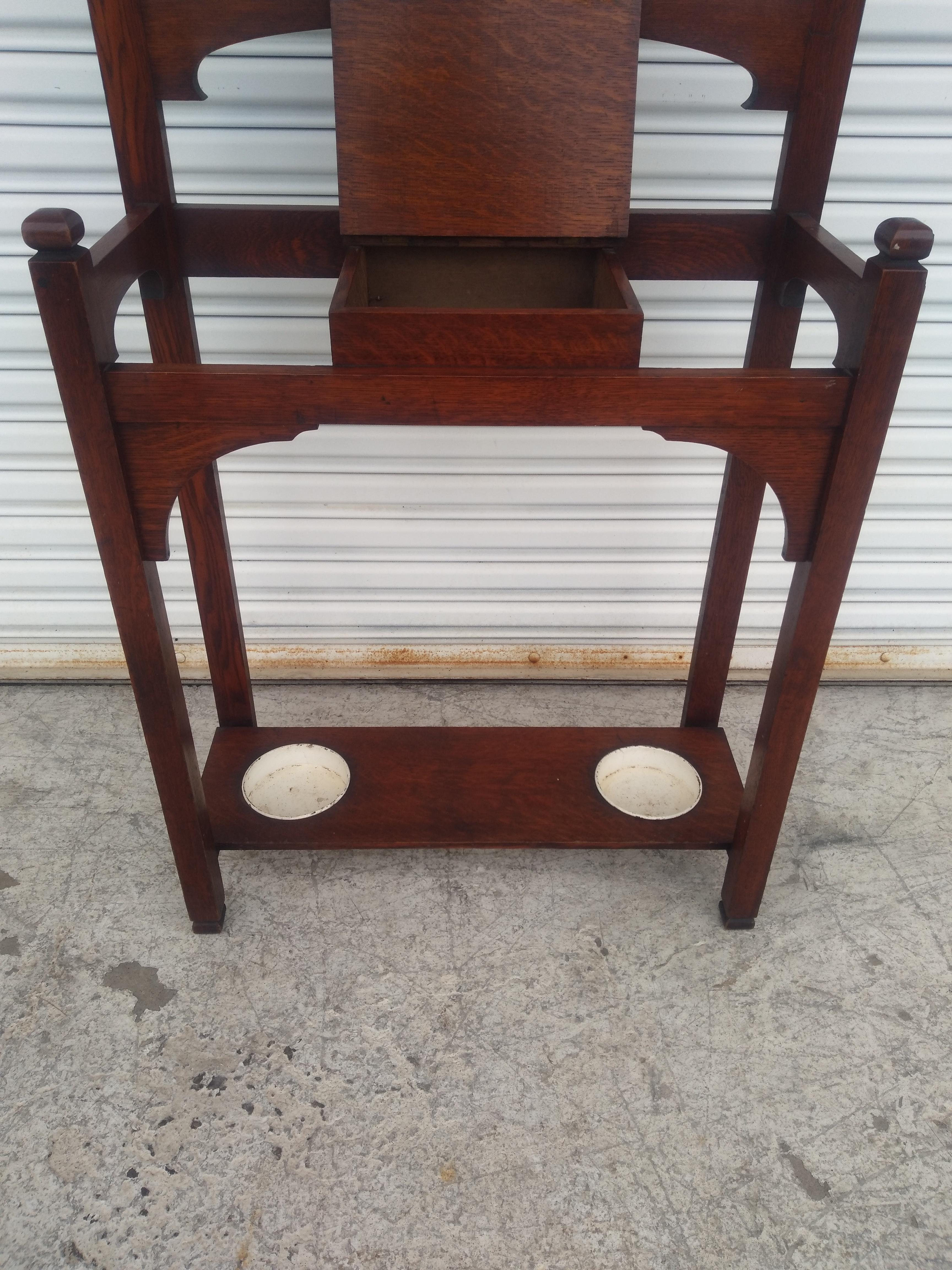 The Arts and Crafts Movement began in the early 20th Century. This is a Mission Oak Hall Tree from that period. This piece is crafted of quarter sawn oak. It has metal hooks for hats and coats. It has a middle storage space for keys and a mirror to