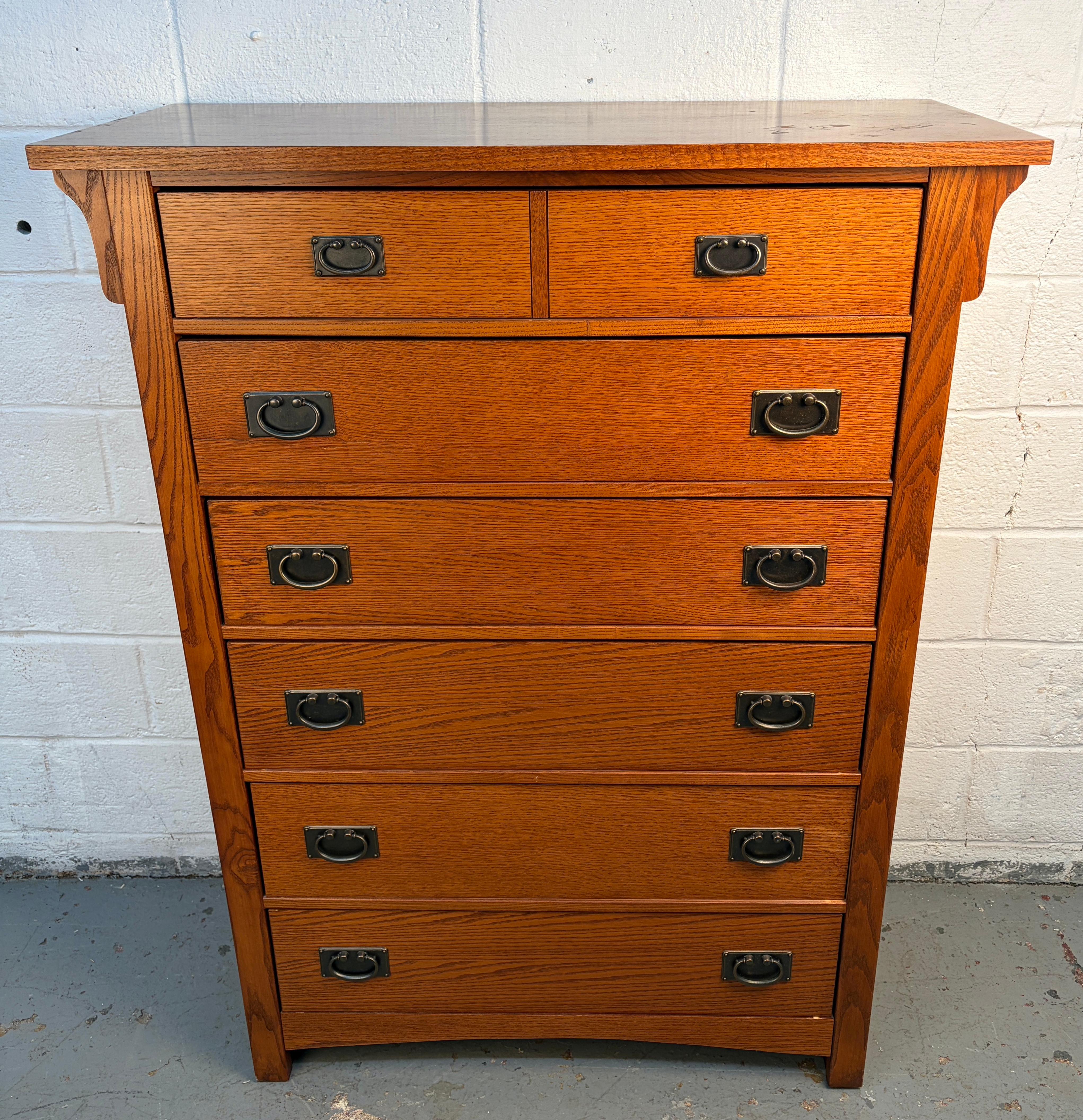 Una cómoda alta de estilo Misión de Vaughan-Bassett, hecha de roble macizo con detalles clásicos de listones verticales. Presenta un perfil alto y elegante con cajones espaciosos que resaltan la calidez y durabilidad del diseño tradicional Arts &