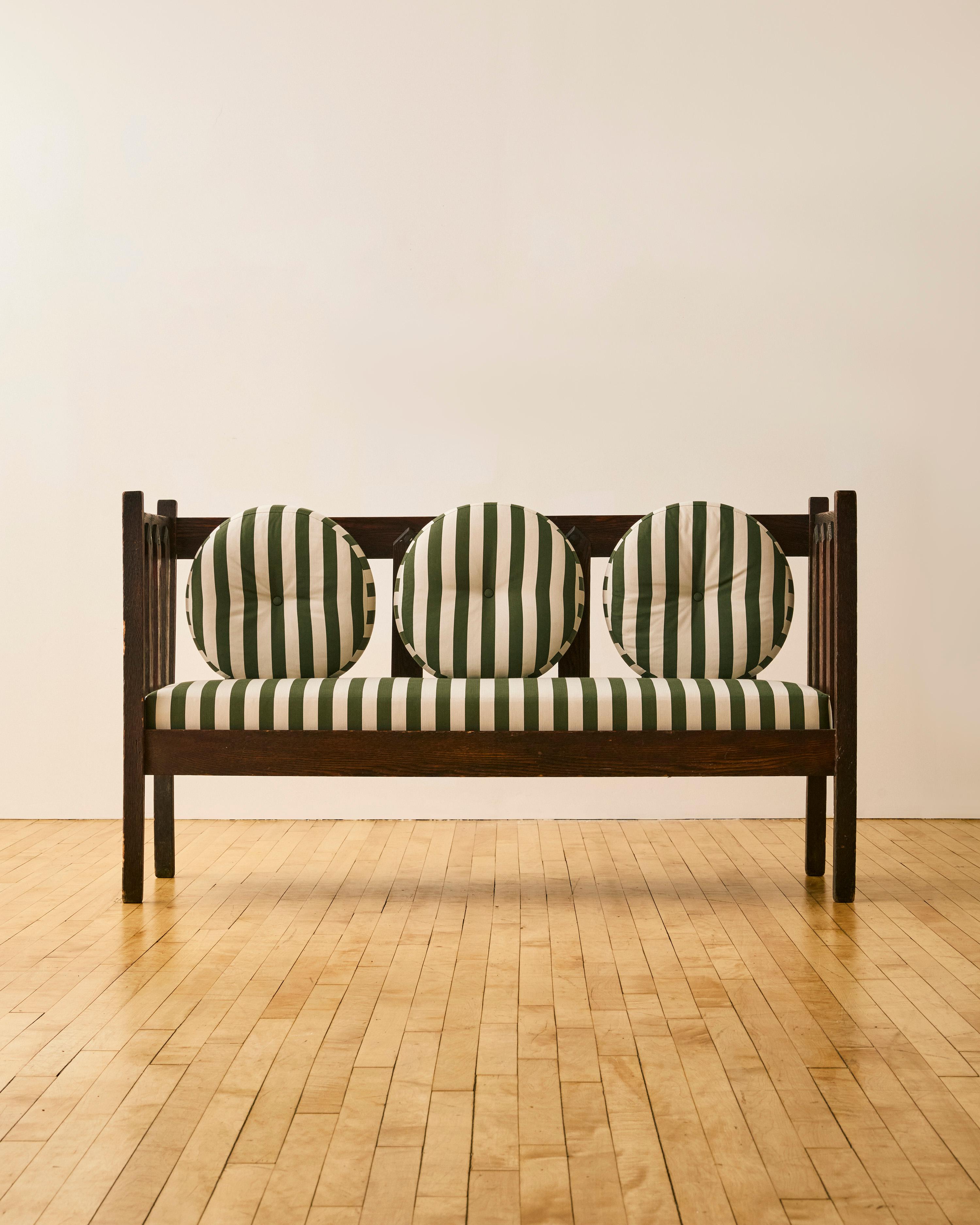 20th Century Mission Oak settee in the style of Gustav Stickley with three removable matching circular bolsters, newly reupholstered in Rogers & Goffigon Dark Green & White striped fabric.