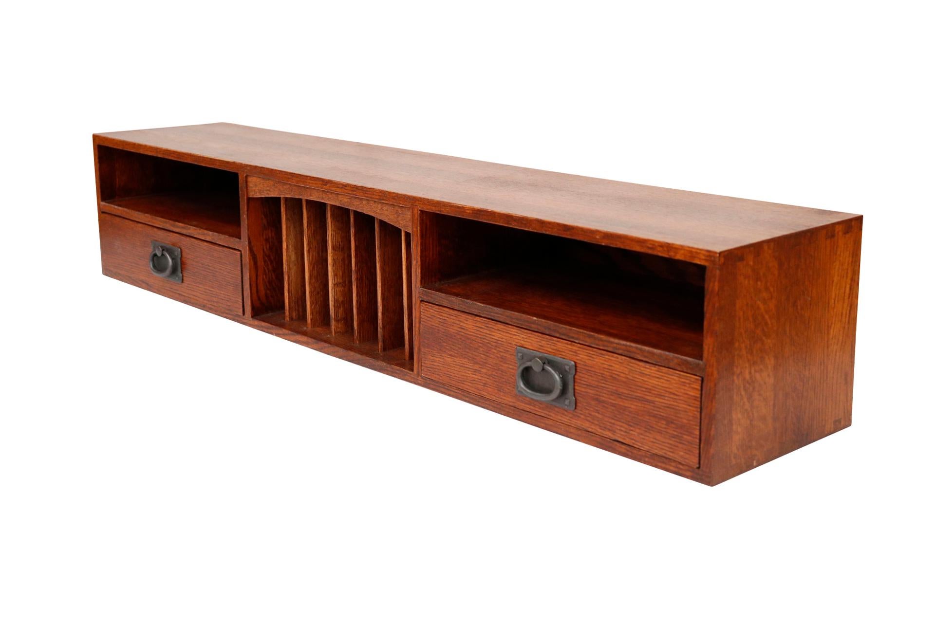 A Mission style desk top organizer. Solid oak wood with rich grain is constructed with dovetailed joints. A slotted organizer in the center is decorated with an arched bracket flanked with a shelf over dovetailed drawers at each side. Drawers open