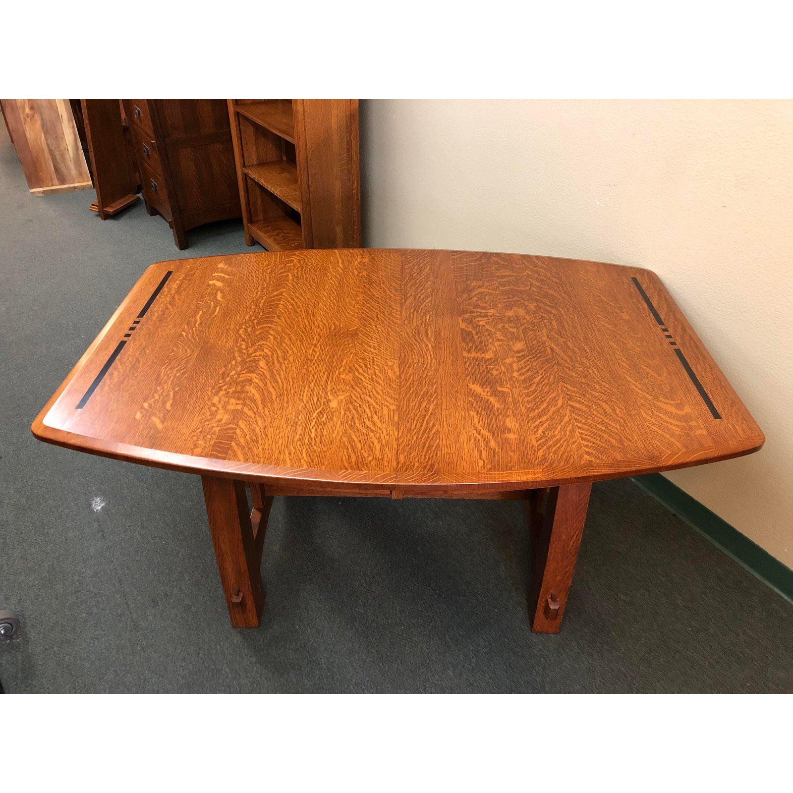 A Colebrook trestle table from The American Bungalow Collection by West Point. A fine Amish craftsmanship. The frame is white oak with a bowed surface shape with black inlays. The legs are curved with a cross inlayed lower support. Comes with one